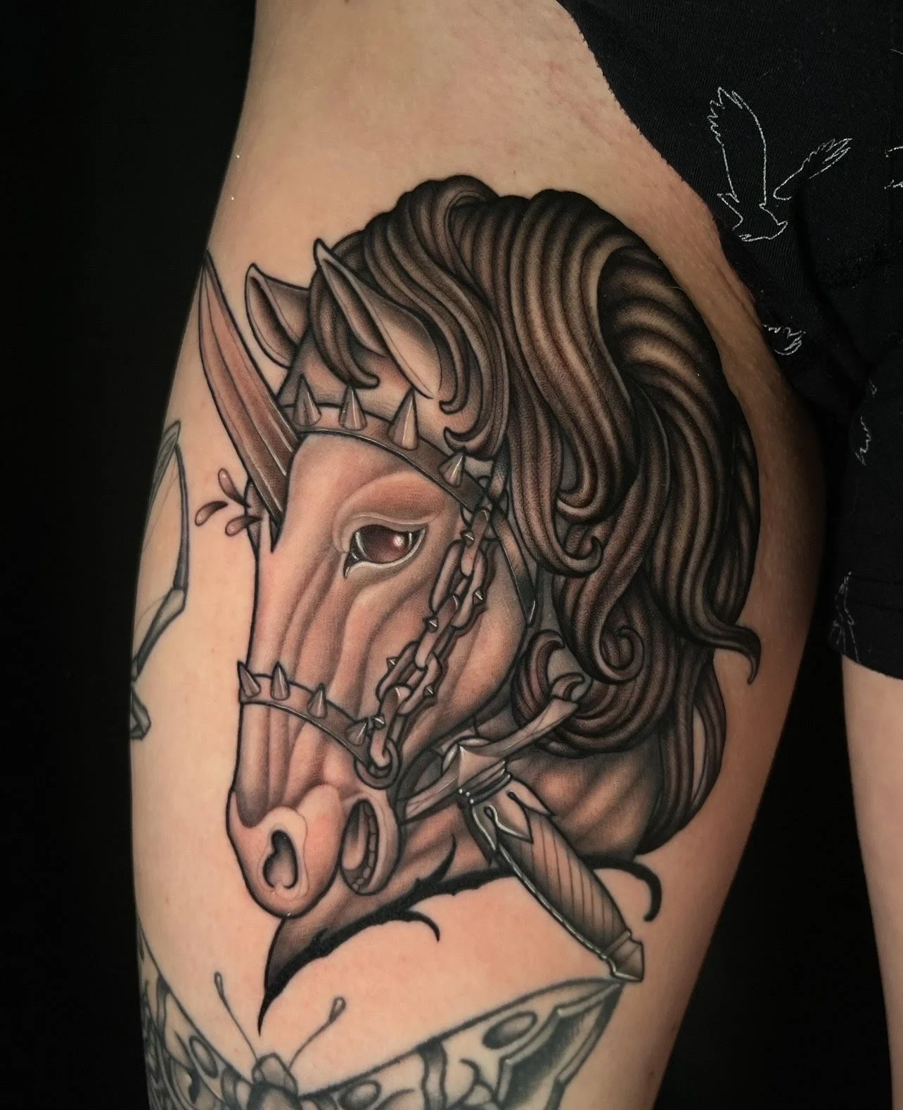 Tattoo of a horse's head with flowing mane, armored with chains and spikes.