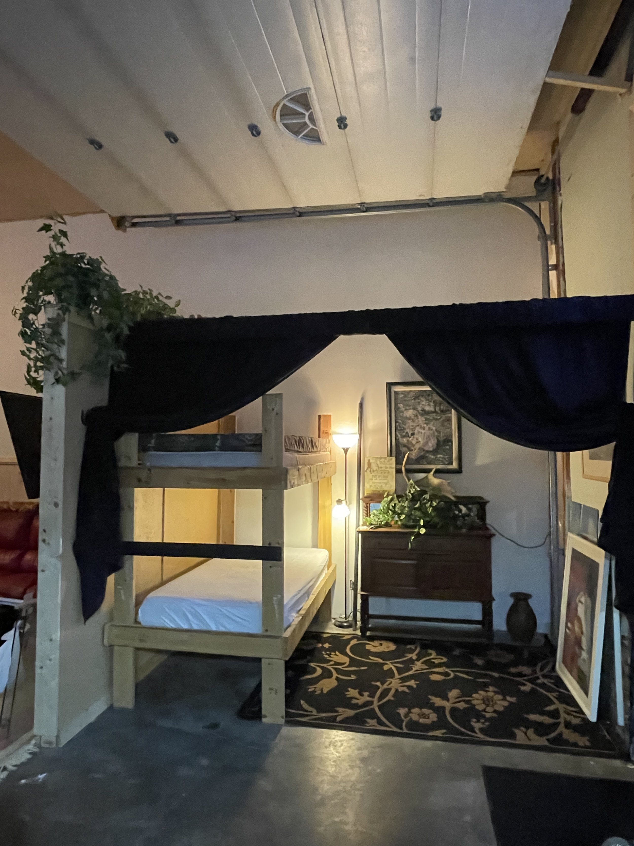 To the right is the first sleeping area, featuring a bunk bed, a side dresser with a lamp and USB plug, fresh bedding, and curtains that provide extra privacy