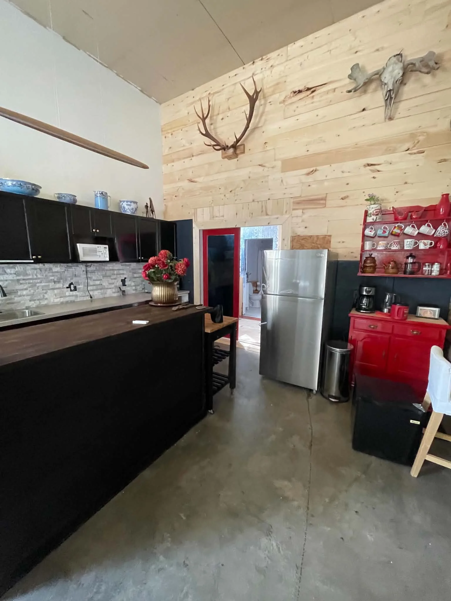 As you continue through the space, a warm, spacious kitchenette greets you with plenty of cupboards, a large island, marble backsplash, and all the cookware you need. Hot and cold water, a brand‑new fridge, a roll‑away island, and a soft hanging LED 