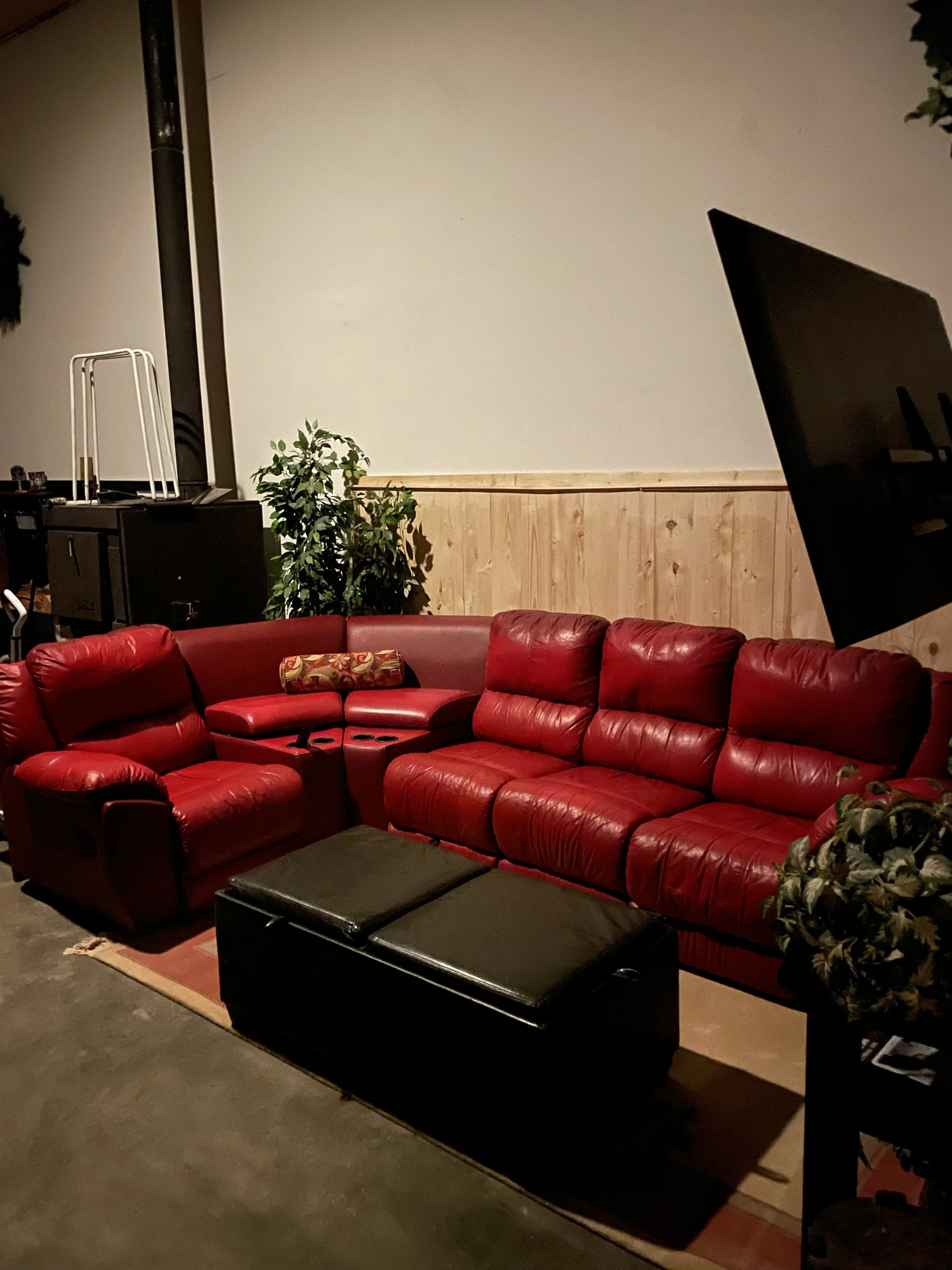 On the right, a red leather L‑shaped reclining sofa faces a 60‑inch smart TV, surrounded by cozy cabin shiplap walls