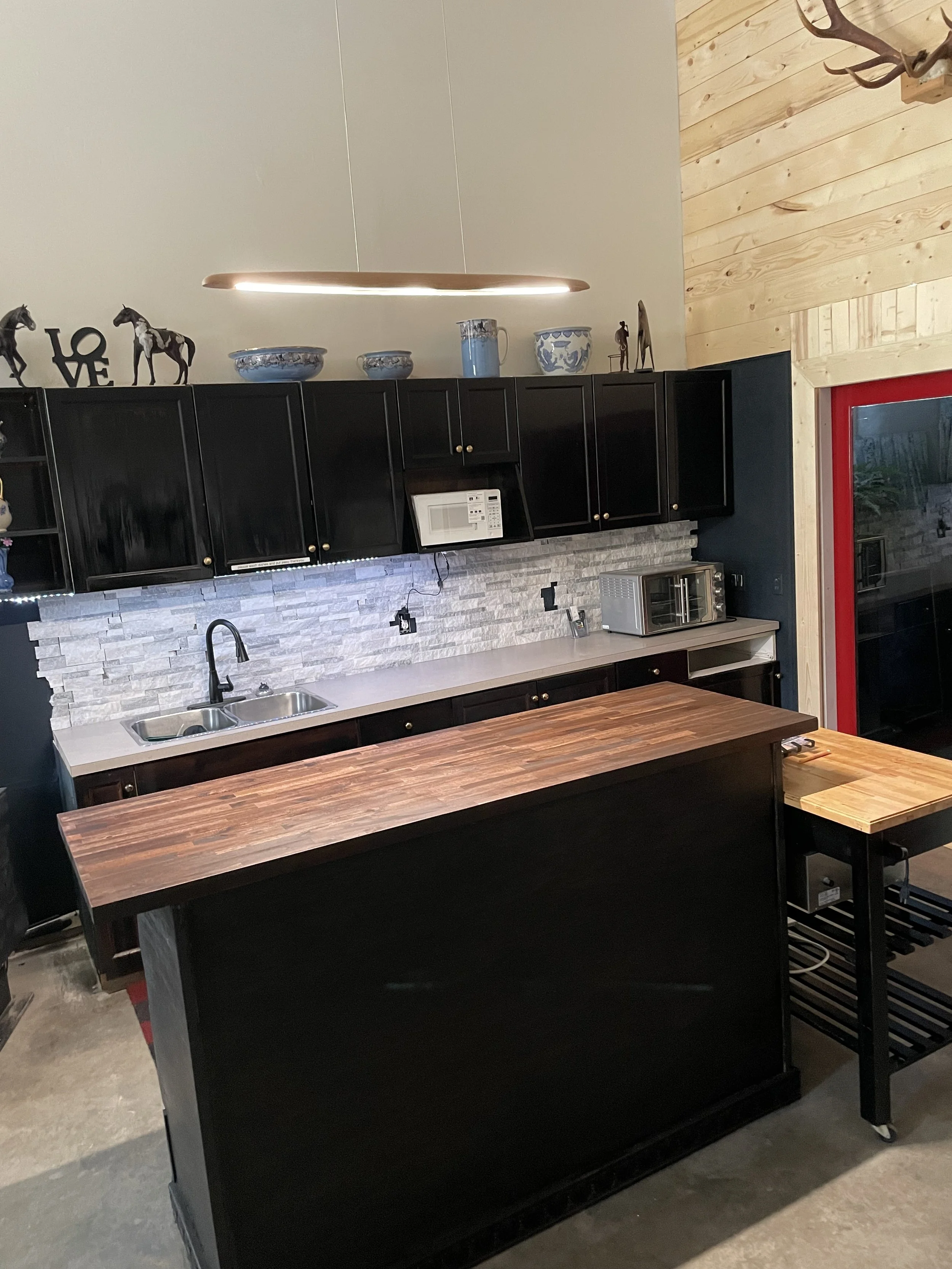 As you continue through the space, a warm, spacious kitchenette greets you with plenty of cupboards, a large island, marble backsplash, and all the cookware and dishes you need. Hot and cold water, a brand‑new fridge, a roll‑away island, and a soft h