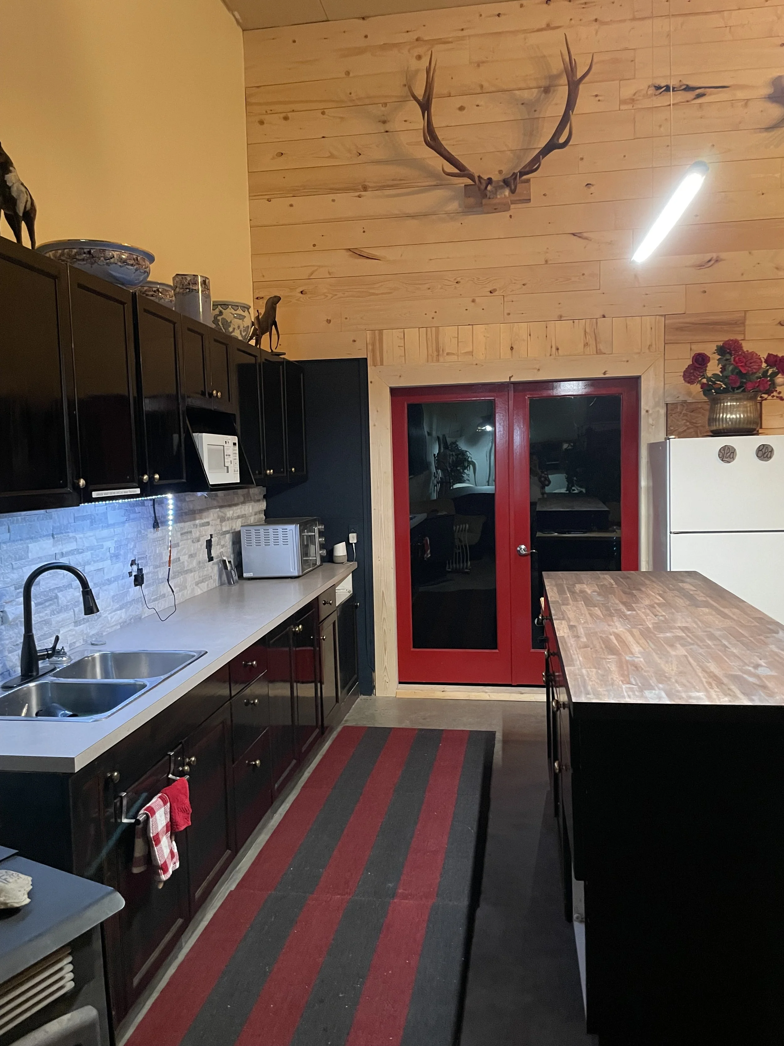 Through the red French doors, the private three‑quarter bathroom sits straight ahead, while the bunk room is just to the right.