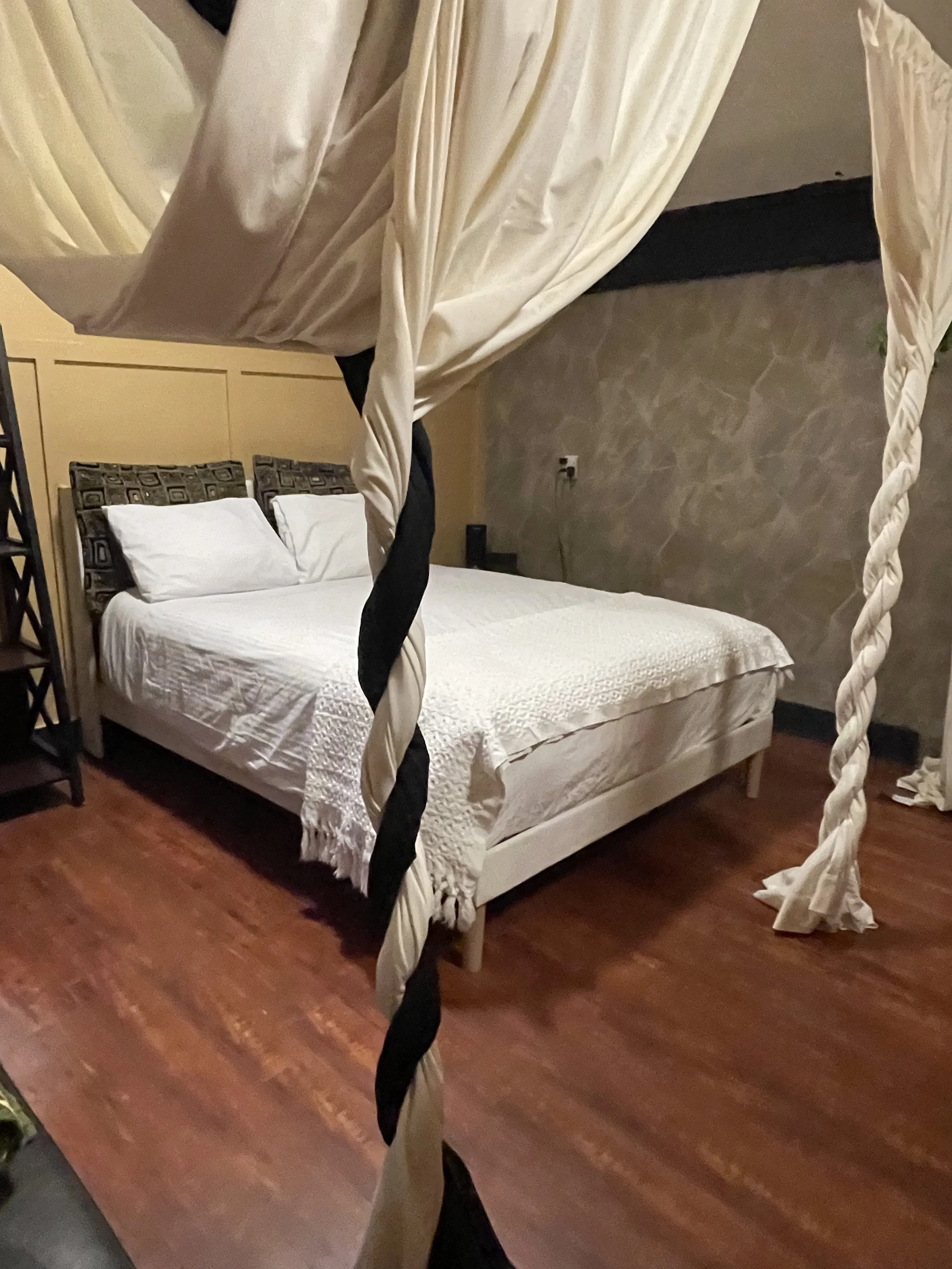 The queen bed features fresh sheets, a duvet with insert, four pillows, and soft privacy curtains that create a cozy retreat within the bunk room.
