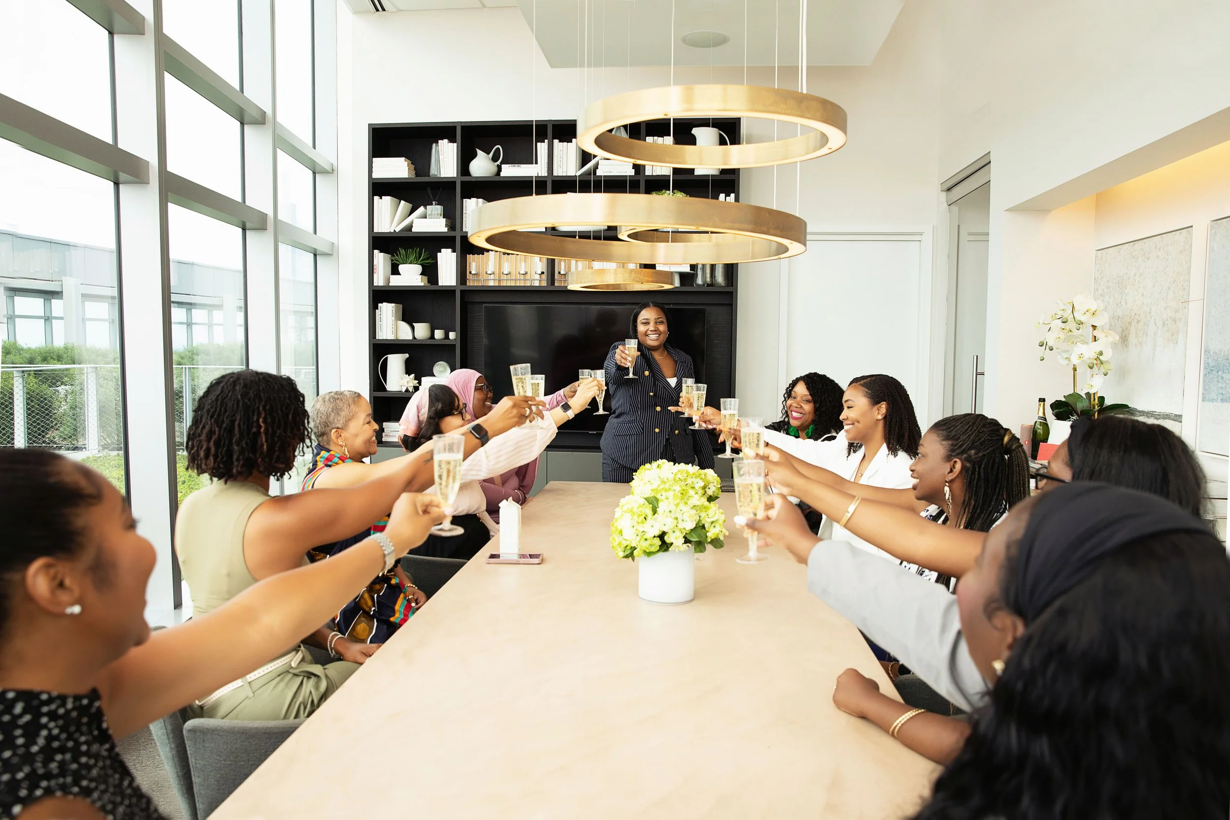 Elite LeadHER Circle members gathered around a table for a celebratory toast
