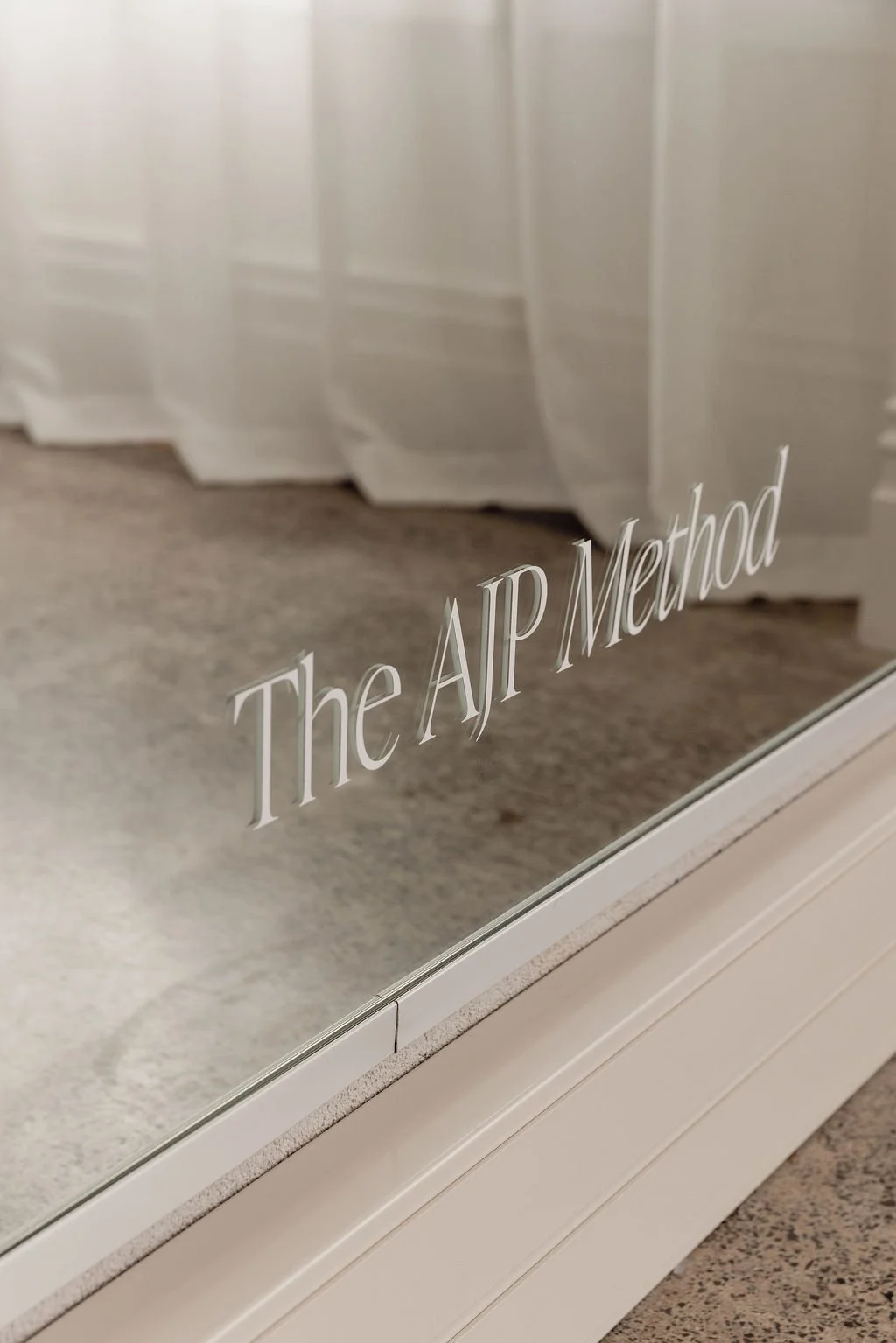 ‘The AJP Method’ written on the studio mirror above a reformer
