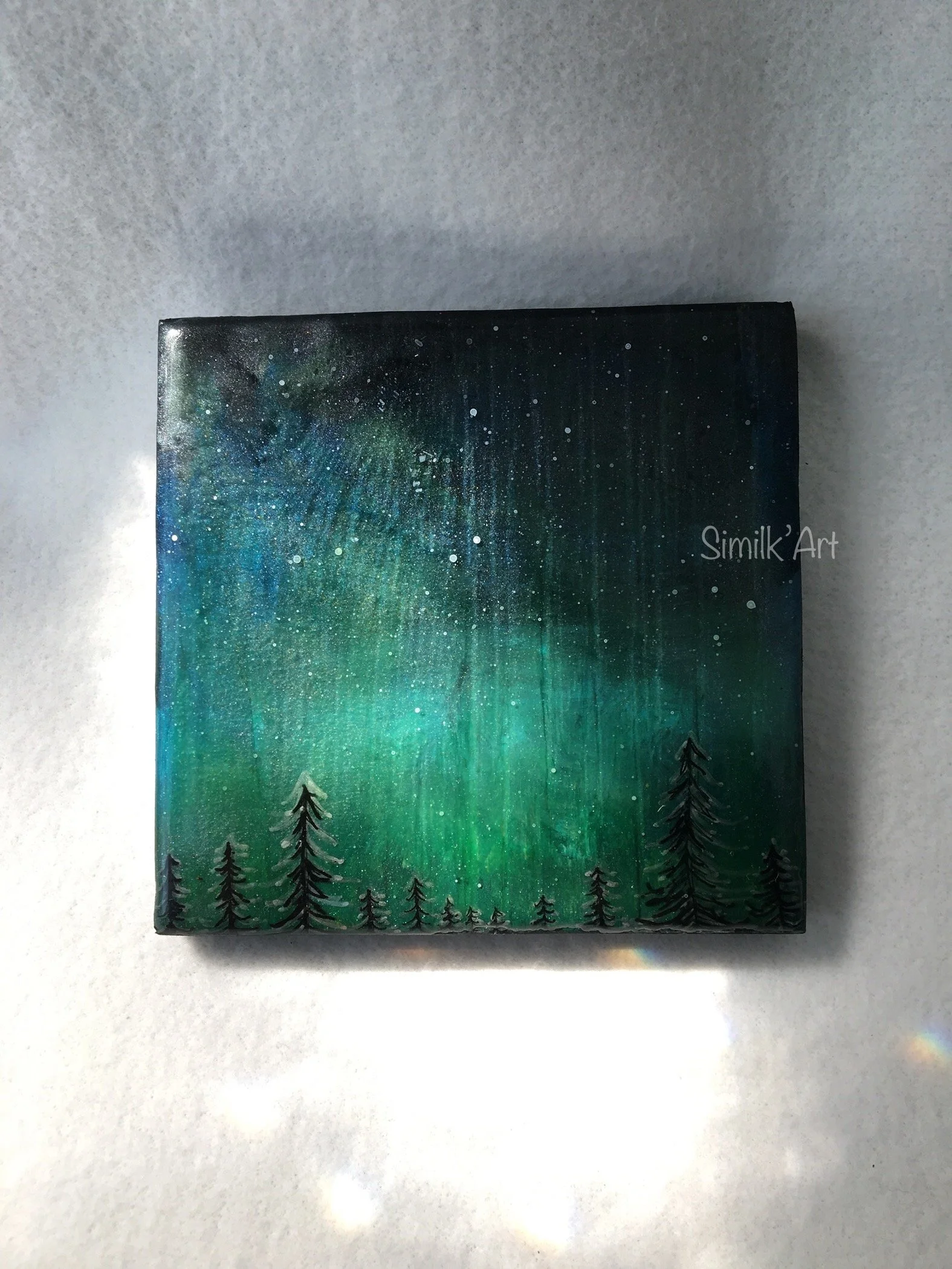 Mini Painting of the Northern Lights over a silhouette of pine trees at night with stars in the sky.