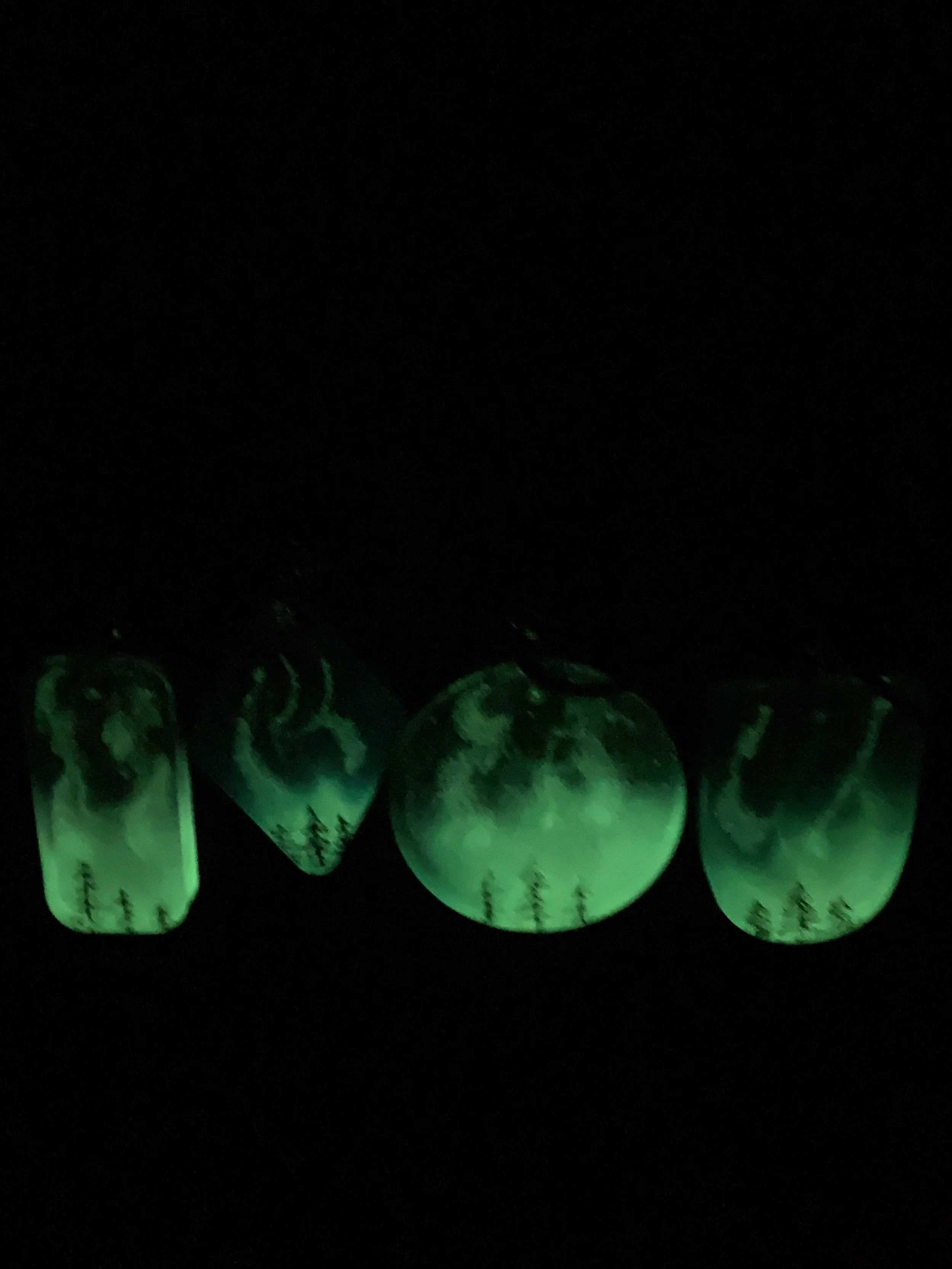 Four glow-in-the-dark pieces in a dark setting, representing the Magical landscape of the Northern Lights