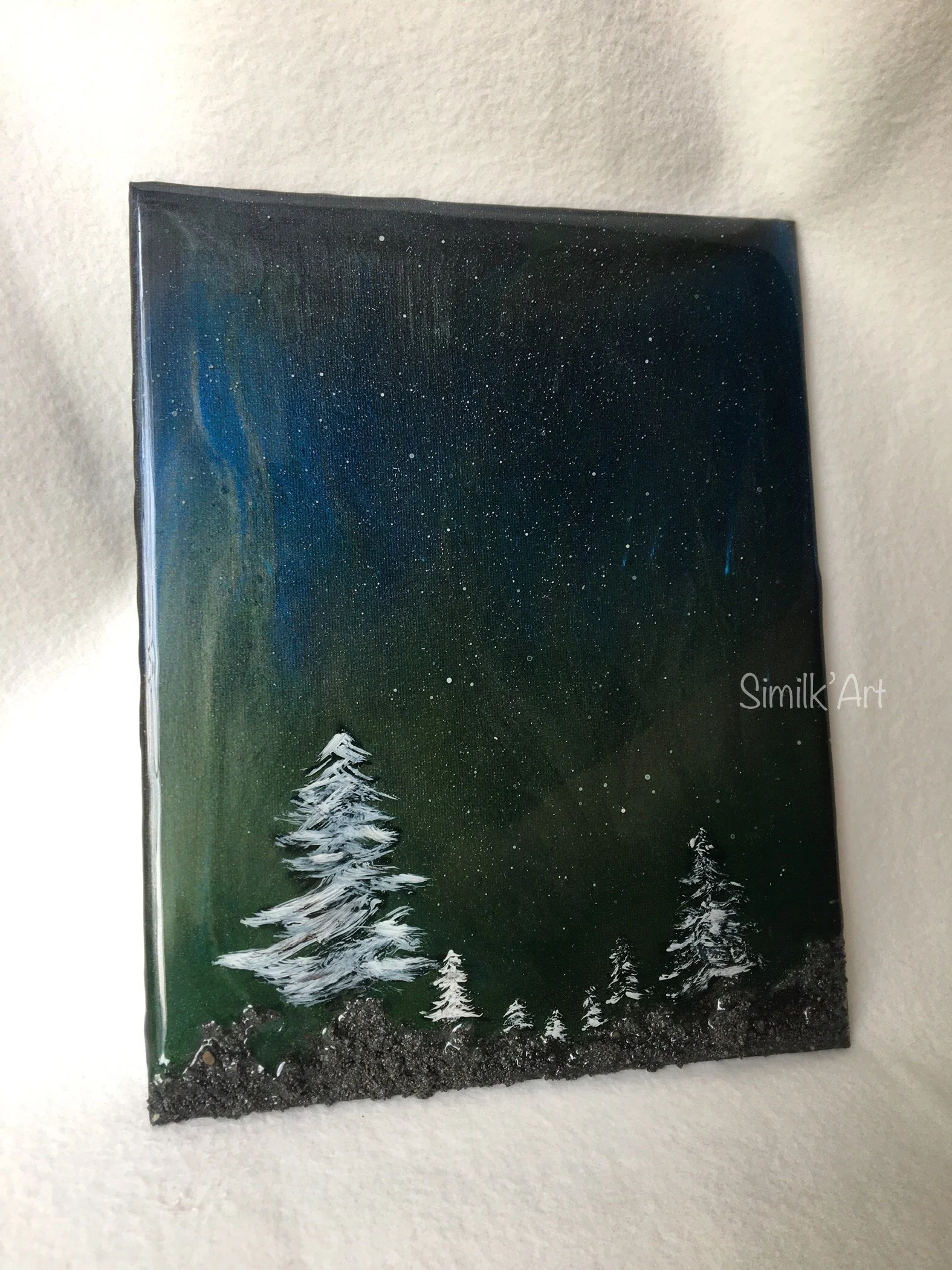 A rectangular glow in the dark landscape painting of a snowy forest under a starry night sky with Northern Lights