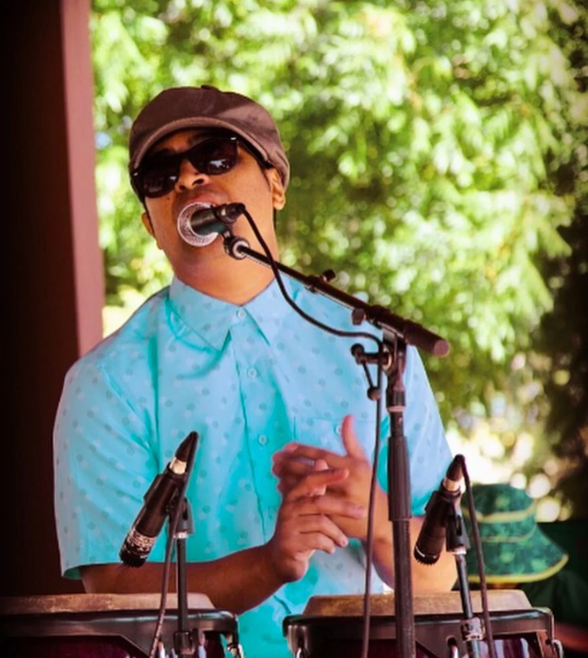 Picture of Steve Diaz singing into a microphone in front of congas
