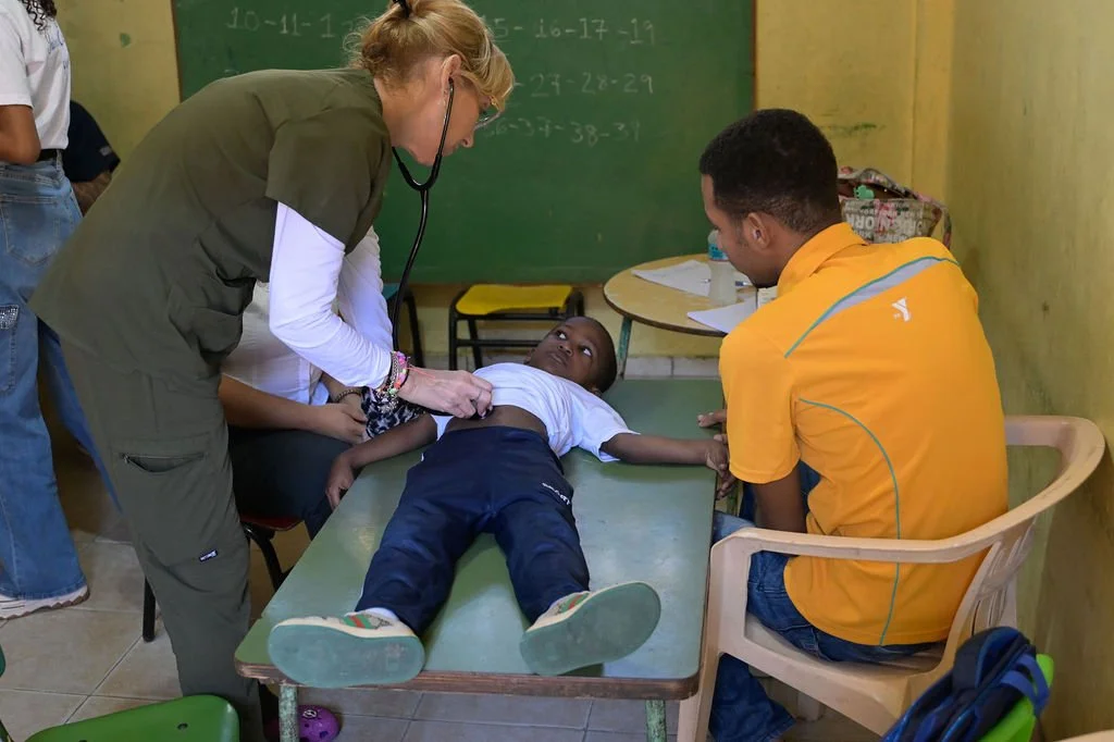 Healthier Futures International volunteer examines a child with a stethoscope on a table during 2026 mission