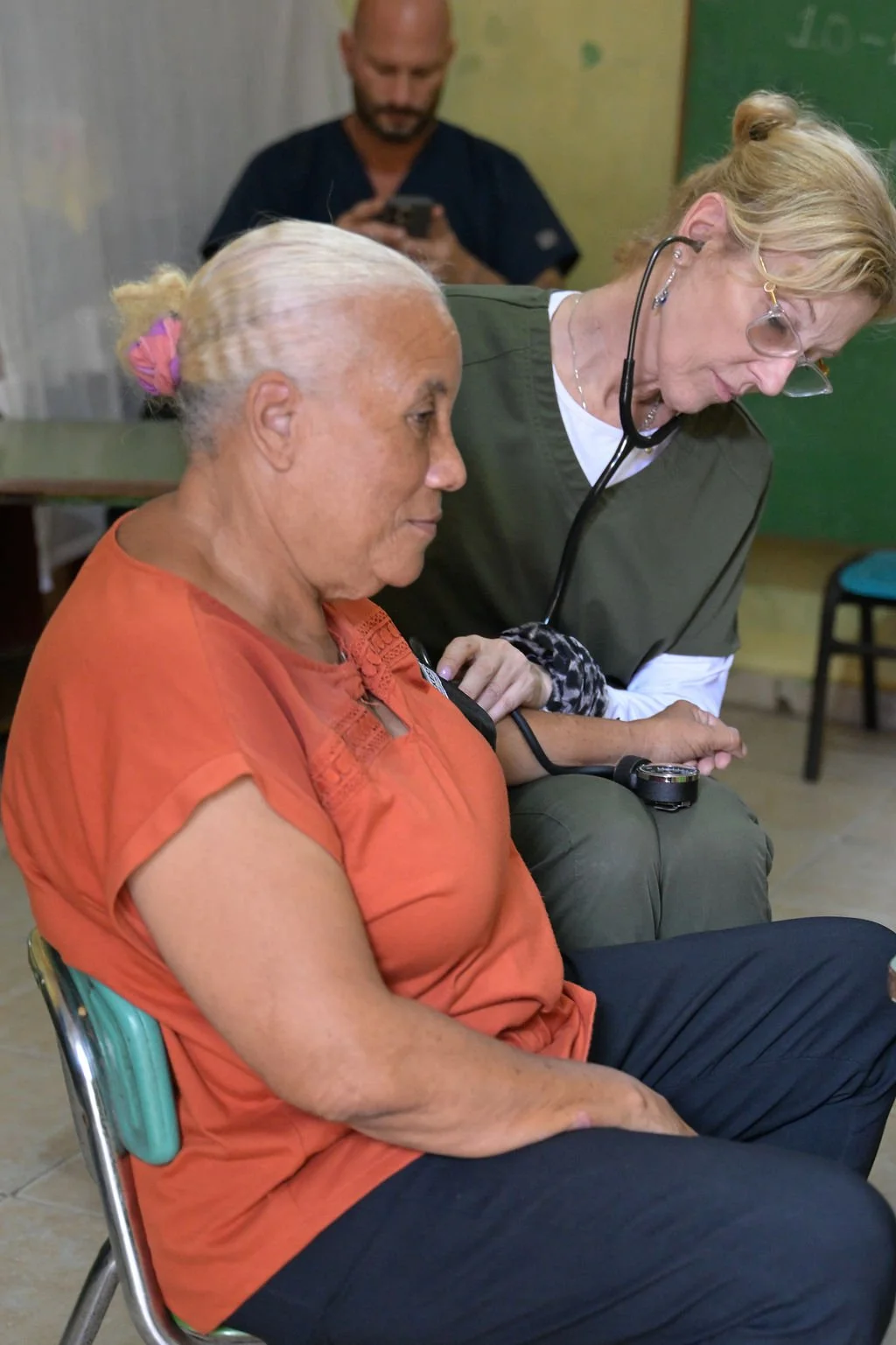 Healthier Futures International volunteer checks a patient's blood pressure with a stethoscope at 2026 clinic
