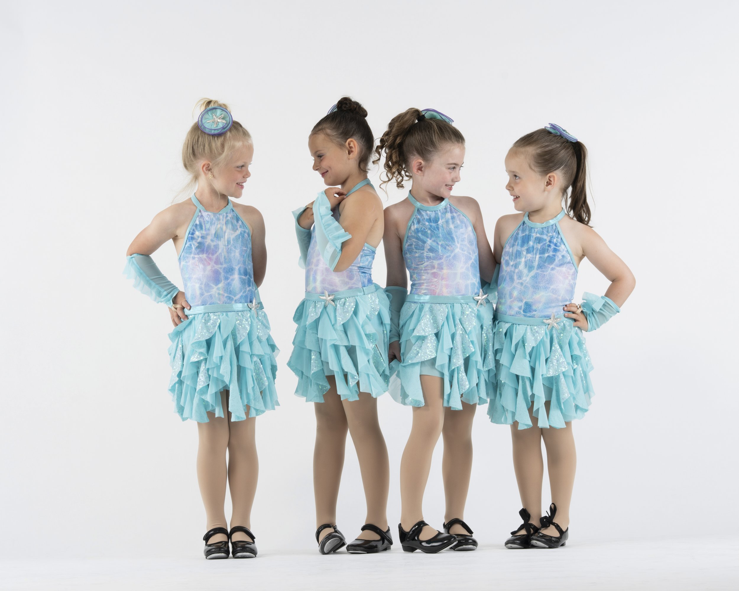 4 young girls in dance costumes in front of a white background