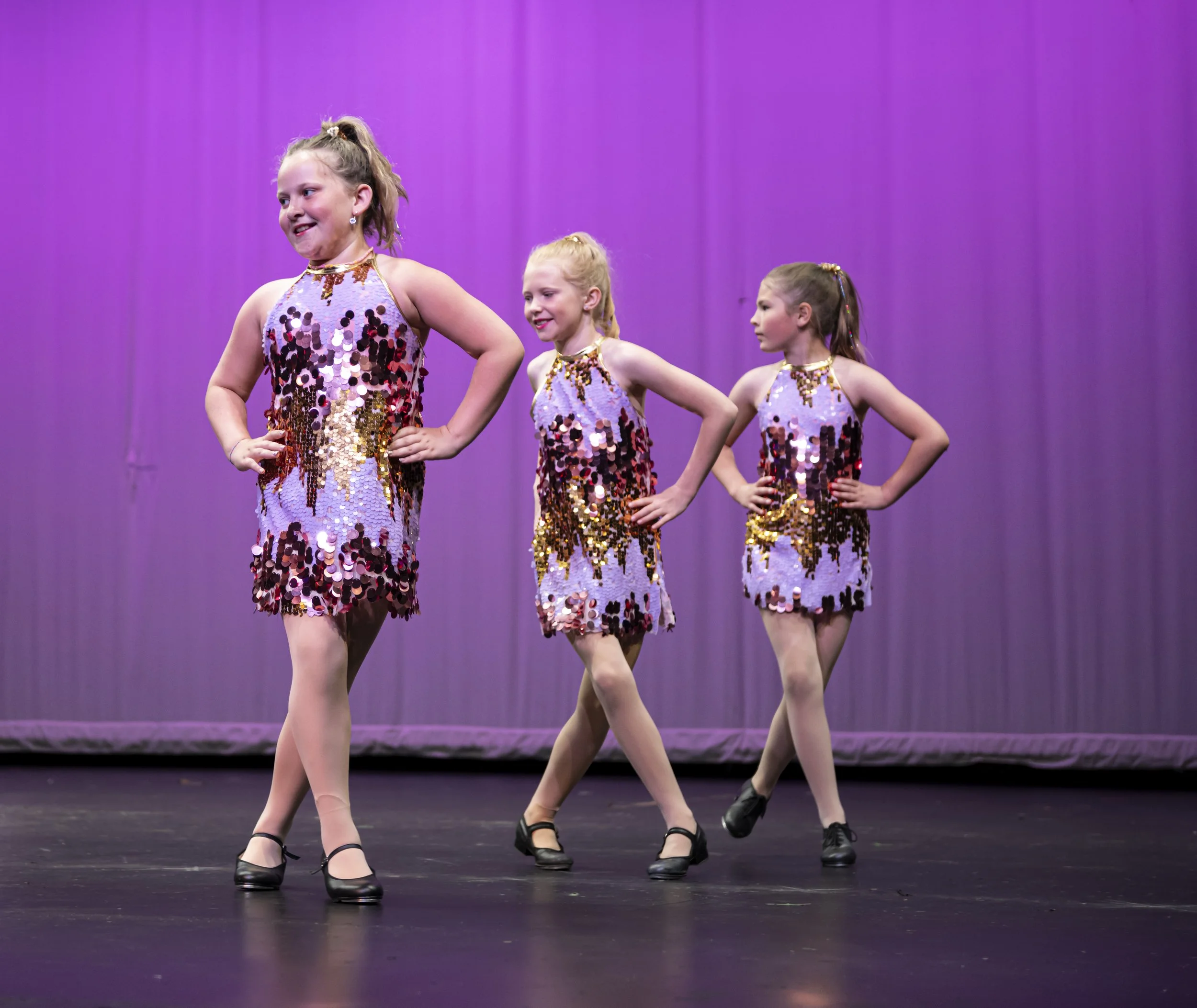 Three young girls on stage at a tap dance recital