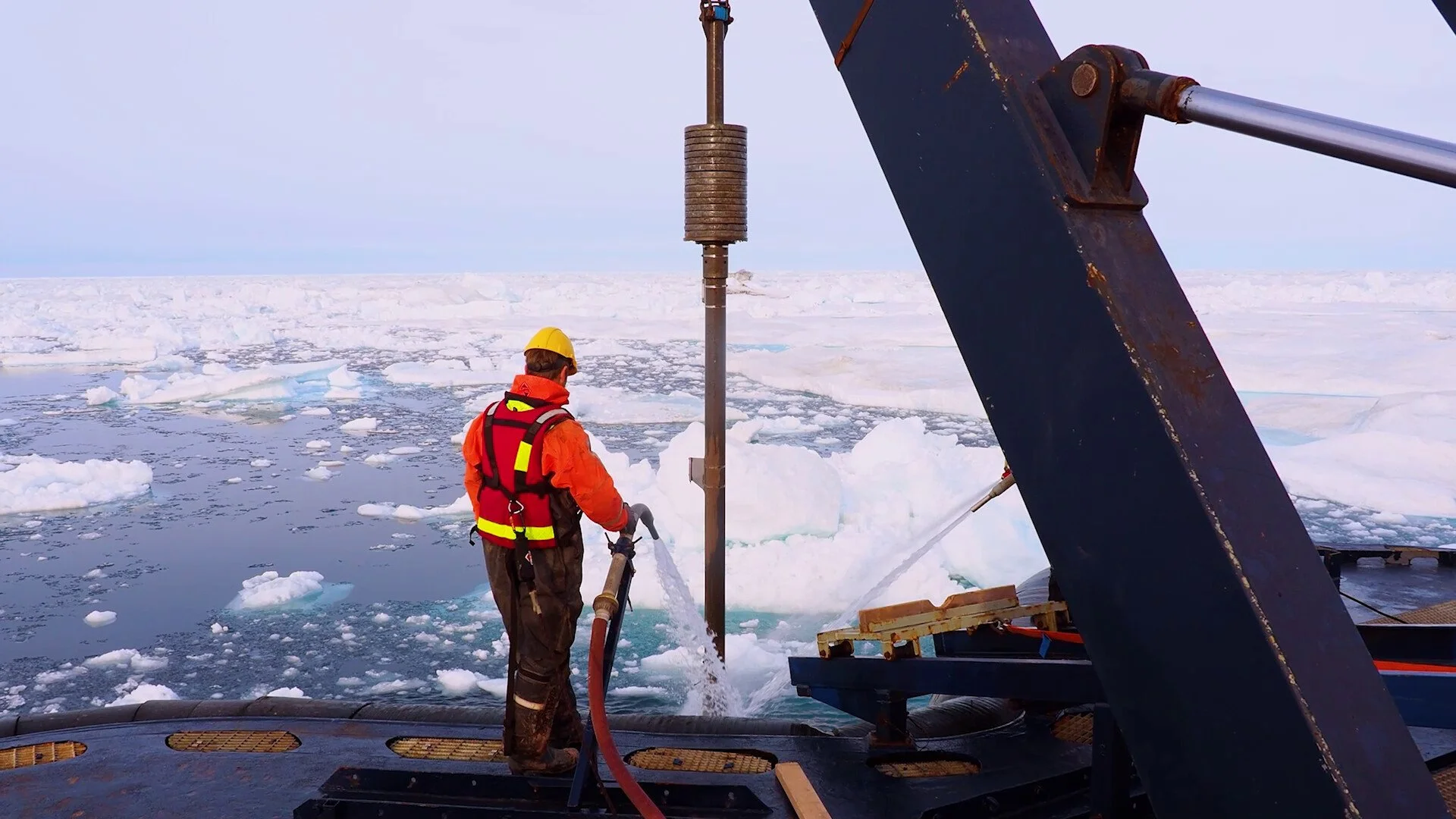 A worker in high-vis uniform on a ship in the ice