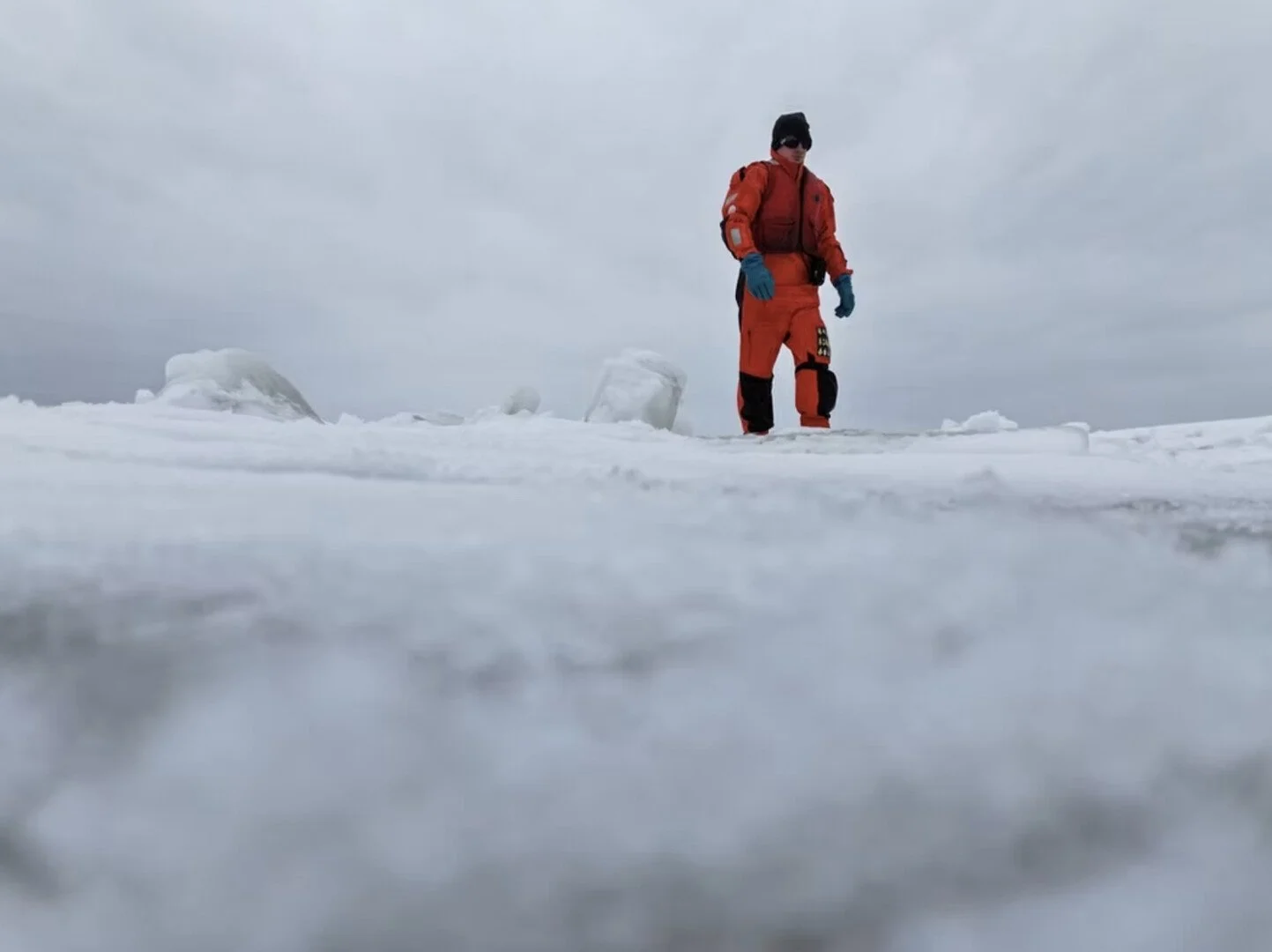 A human figure in an orange suit walking on ice