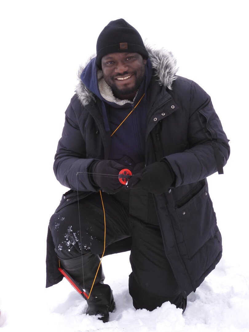 A man in a jacket and fur hat poses in the snow