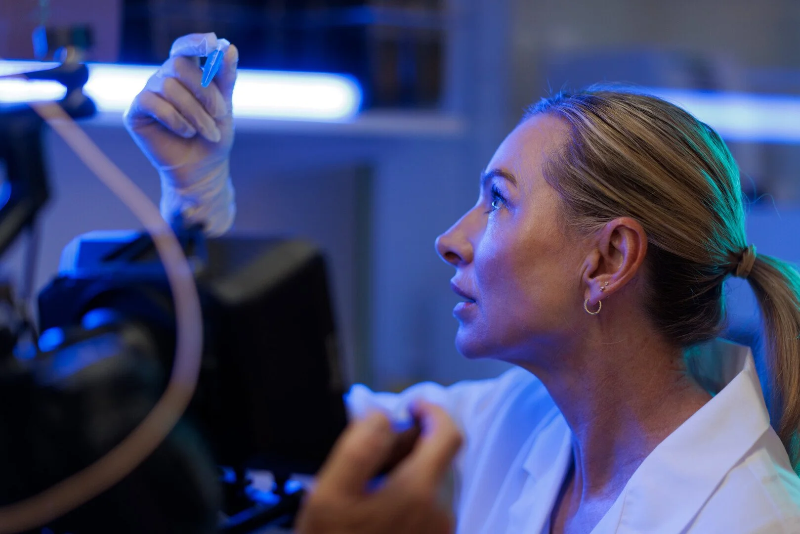 A woman in a white lab coat inspects equipment