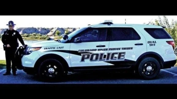 Colorado River Know Trails police traffic unit vehicle and a police officer standing next to it.