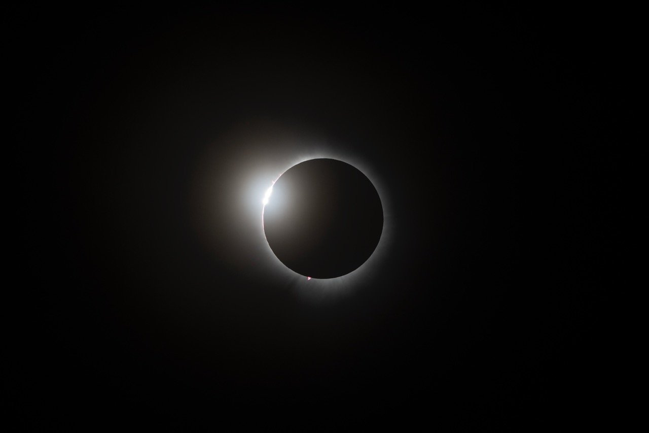 A solar eclipse showing the moon covering the sun, with a bright halo around the dark moon.