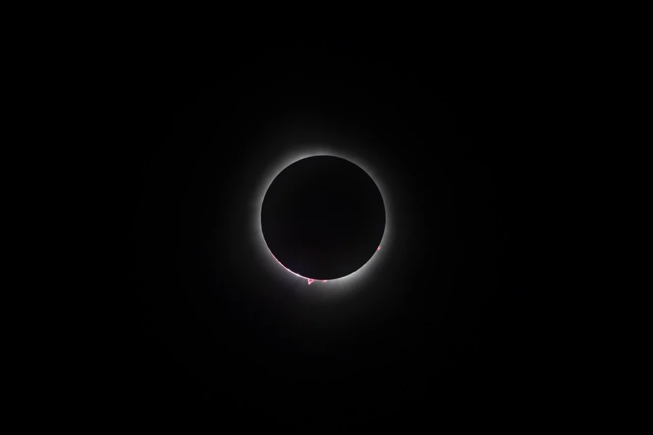 A solar eclipse with the moon covering the sun, creating a dark circle with a bright ring around it.