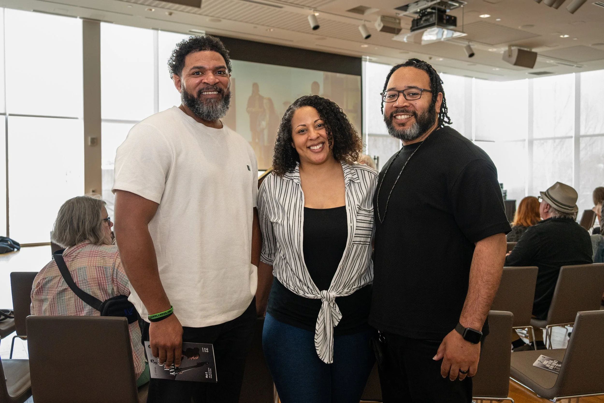 Three people standing together and smiling at an indoor event.