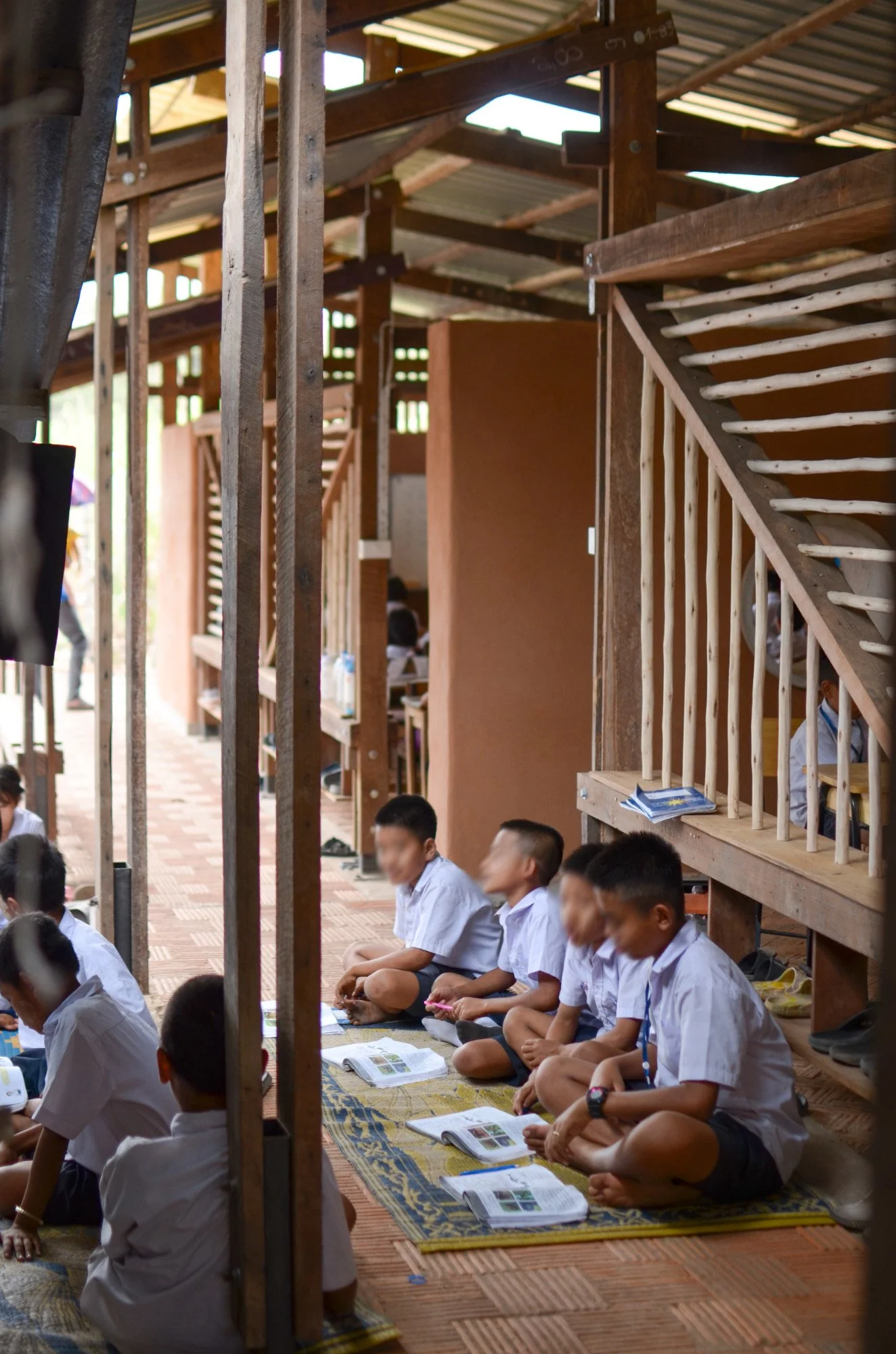 Schüler sitzen im Meditationsraum eines Tempels, meditative Übungen, Bücher vor ihnen, unter einem Holzdach, Holzstufen und Schüler in Schuluniformen