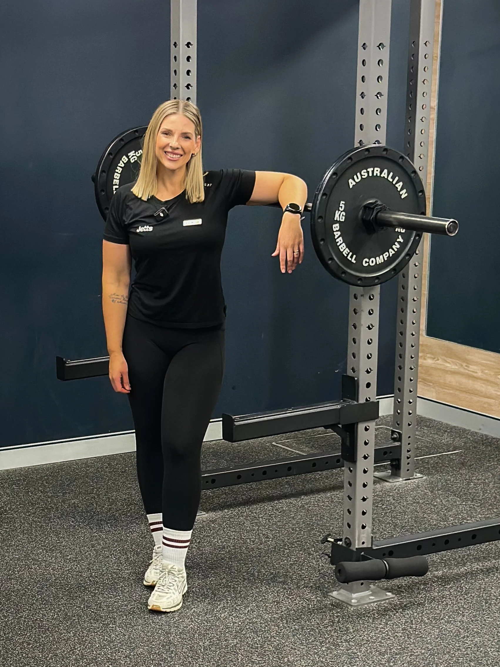 Coach standing in gym against weight barbell