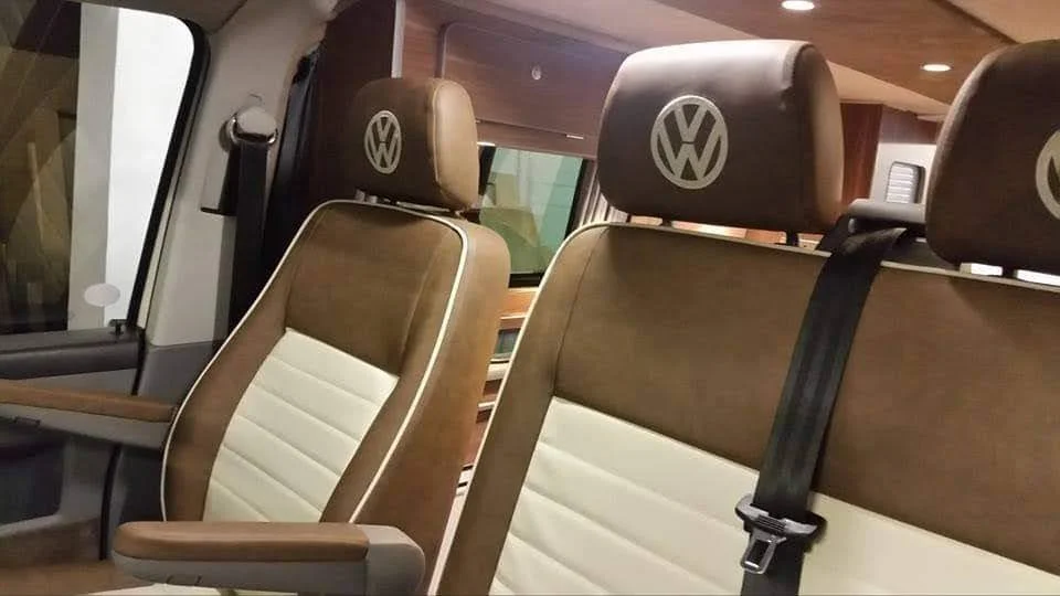 Inside a Volkswagen vehicle, showing brown and white seats with Volkswagen logos on the headrests.