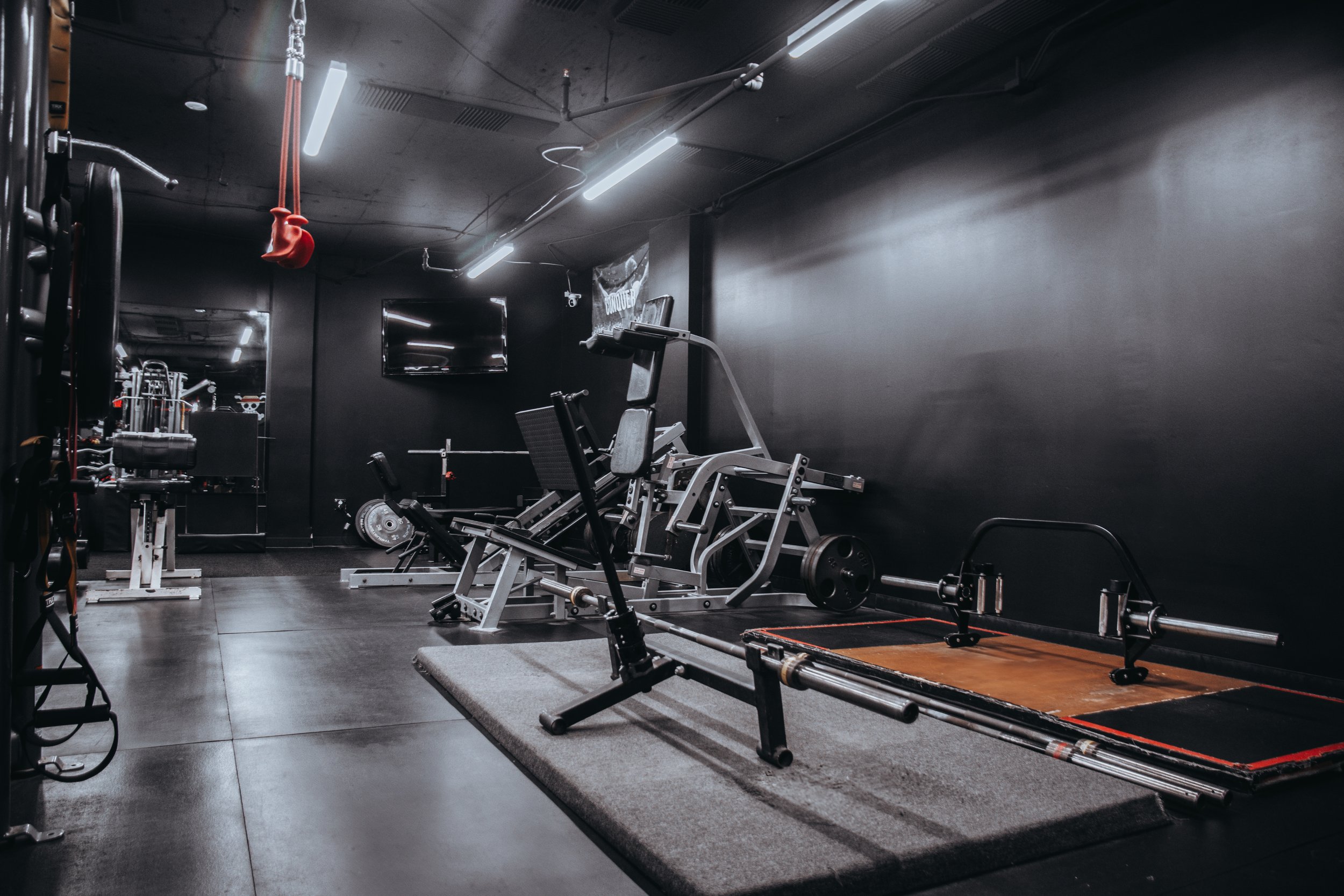 Empty gym with workout machines, weights, and a red gymnastic ring hanging from the ceiling.
