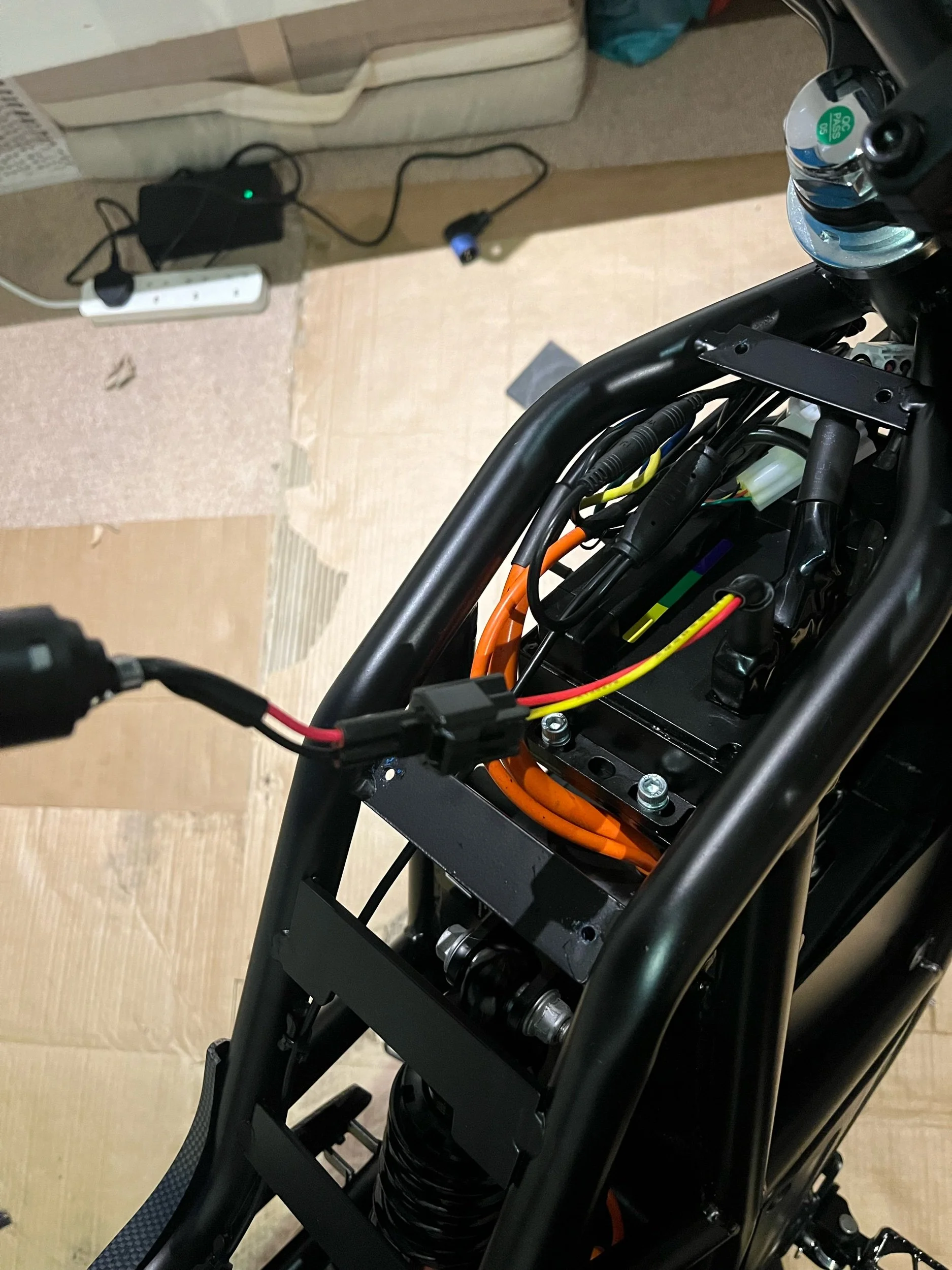 Close-up of an electric bike's frame with visible wiring, motor components, and a water bottle attached to the frame.