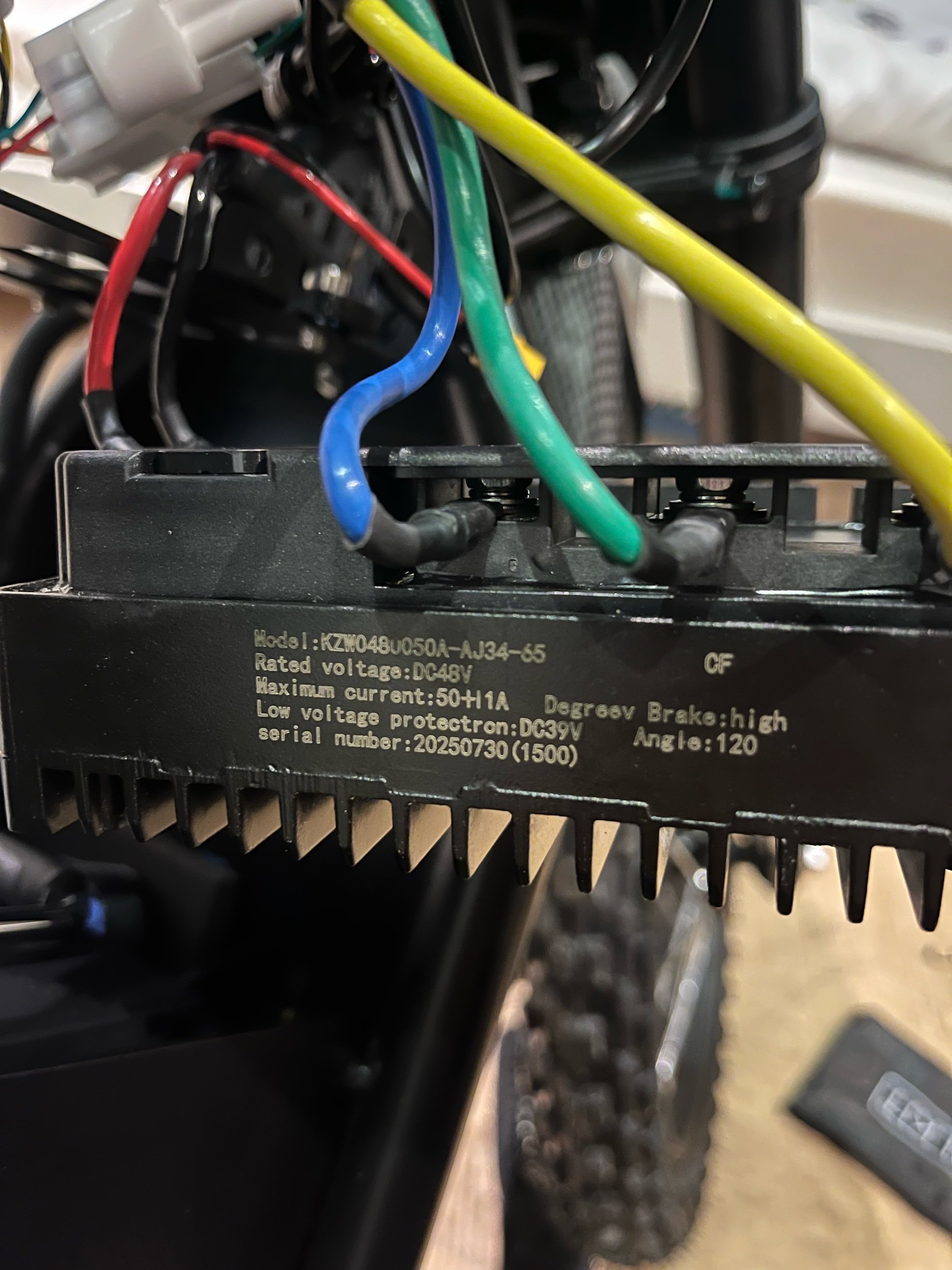 Close-up of an electronic controller with multiple colored wires connected to it, mounted on a machine, possibly a motorcycle or similar vehicle.