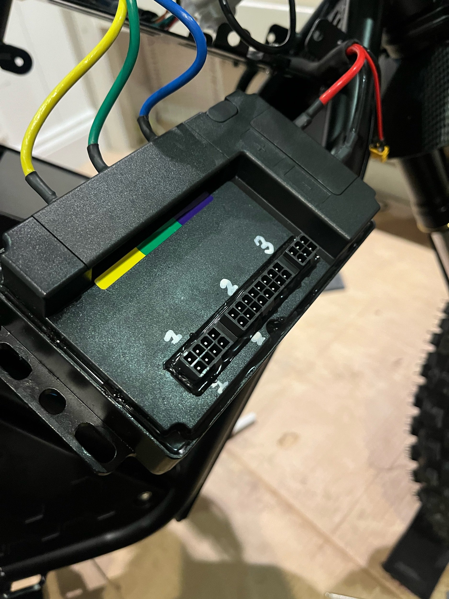 Close-up of a black electronic control unit with colored wiring and numbered connectors.