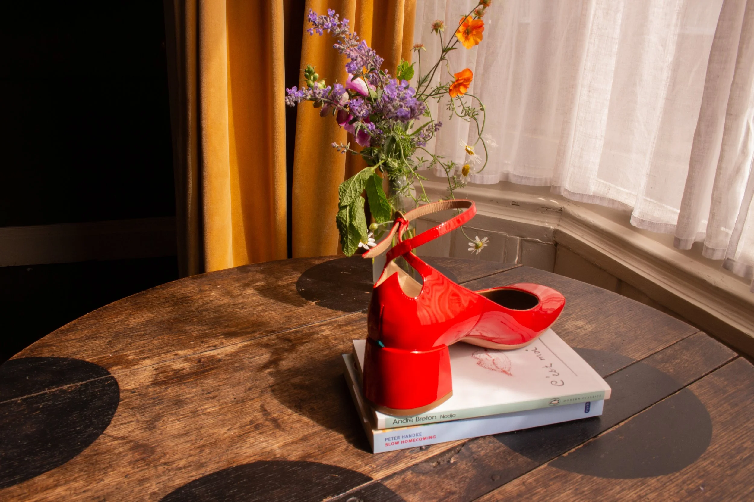 Designer red shoe styled on a reclaimed table at Dot Cottage showcasing characterful interiors for photography and film shoots