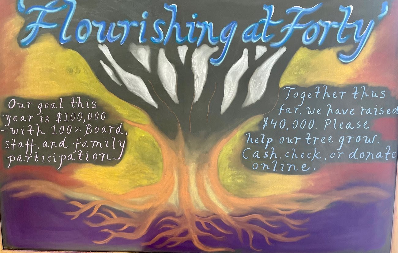 Colorful chalkboard artwork featuring a large tree with white leaves and roots. The title reads 'Flourishing at Forty' in blue cursive. Text on the left side says, 'Our goal this year is $100,000 with 100% board, staff, and family participation.' The