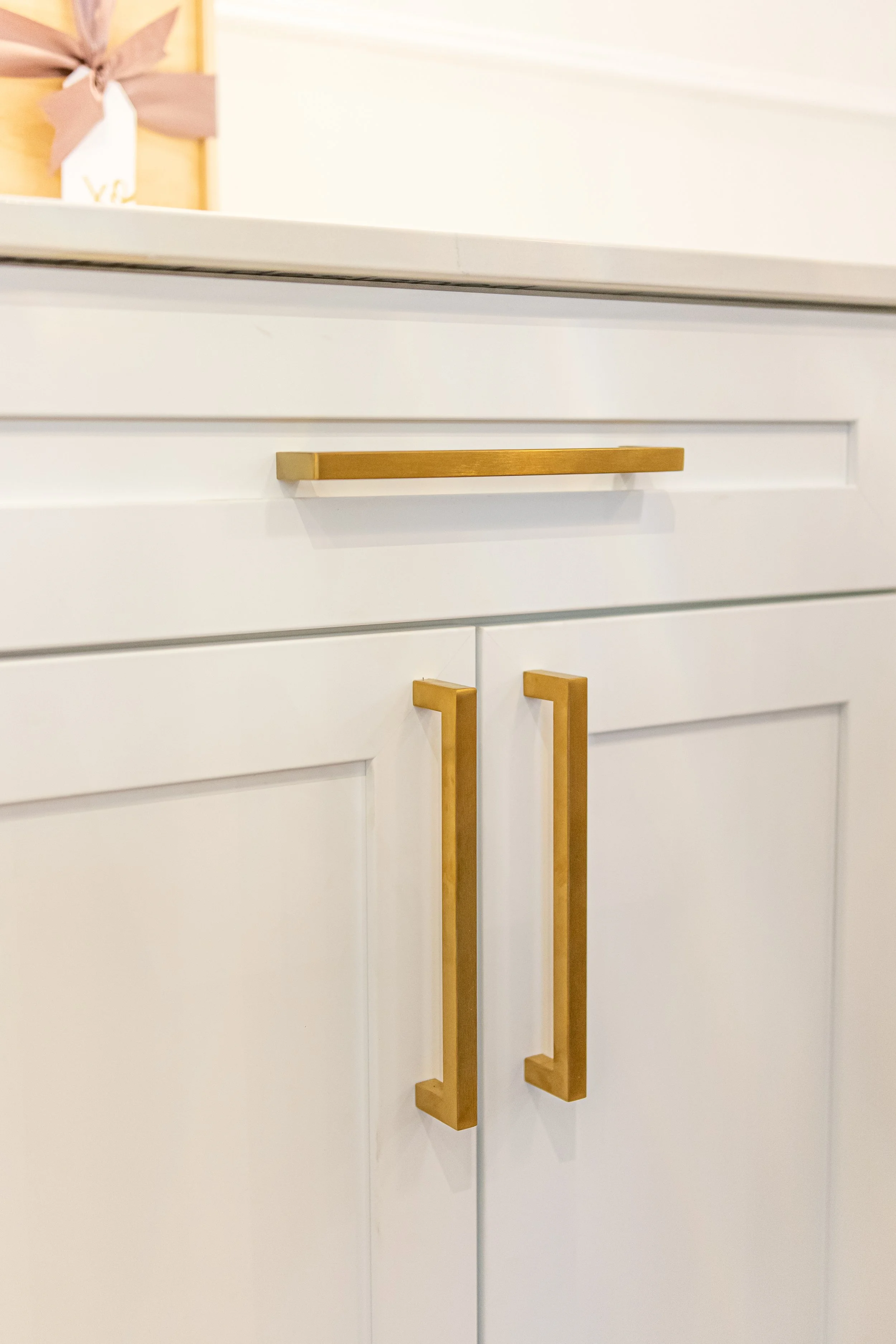 Close-up of white kitchen cabinets with gold handles.