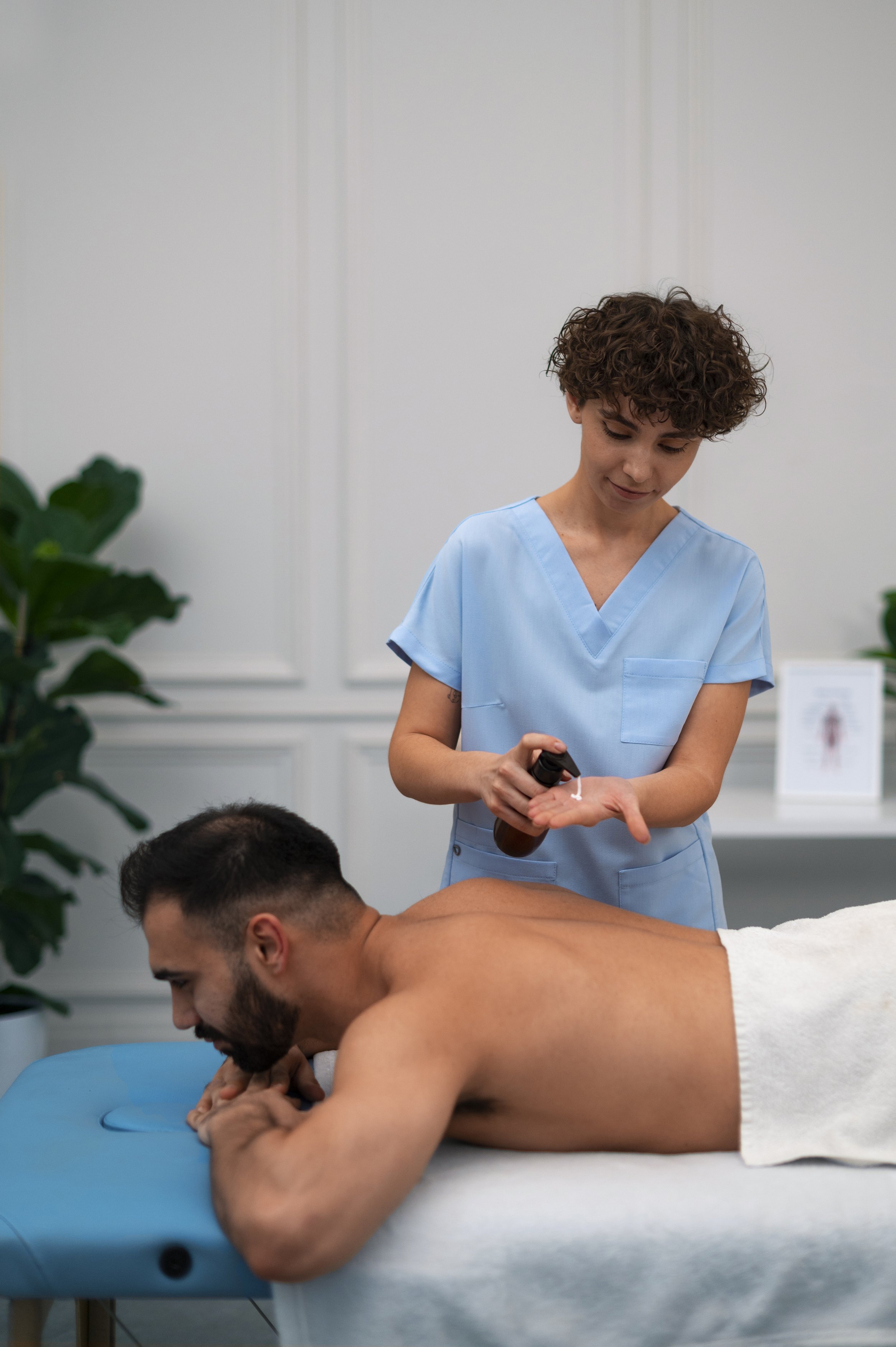 Therapist preparing massage oil for a male client.