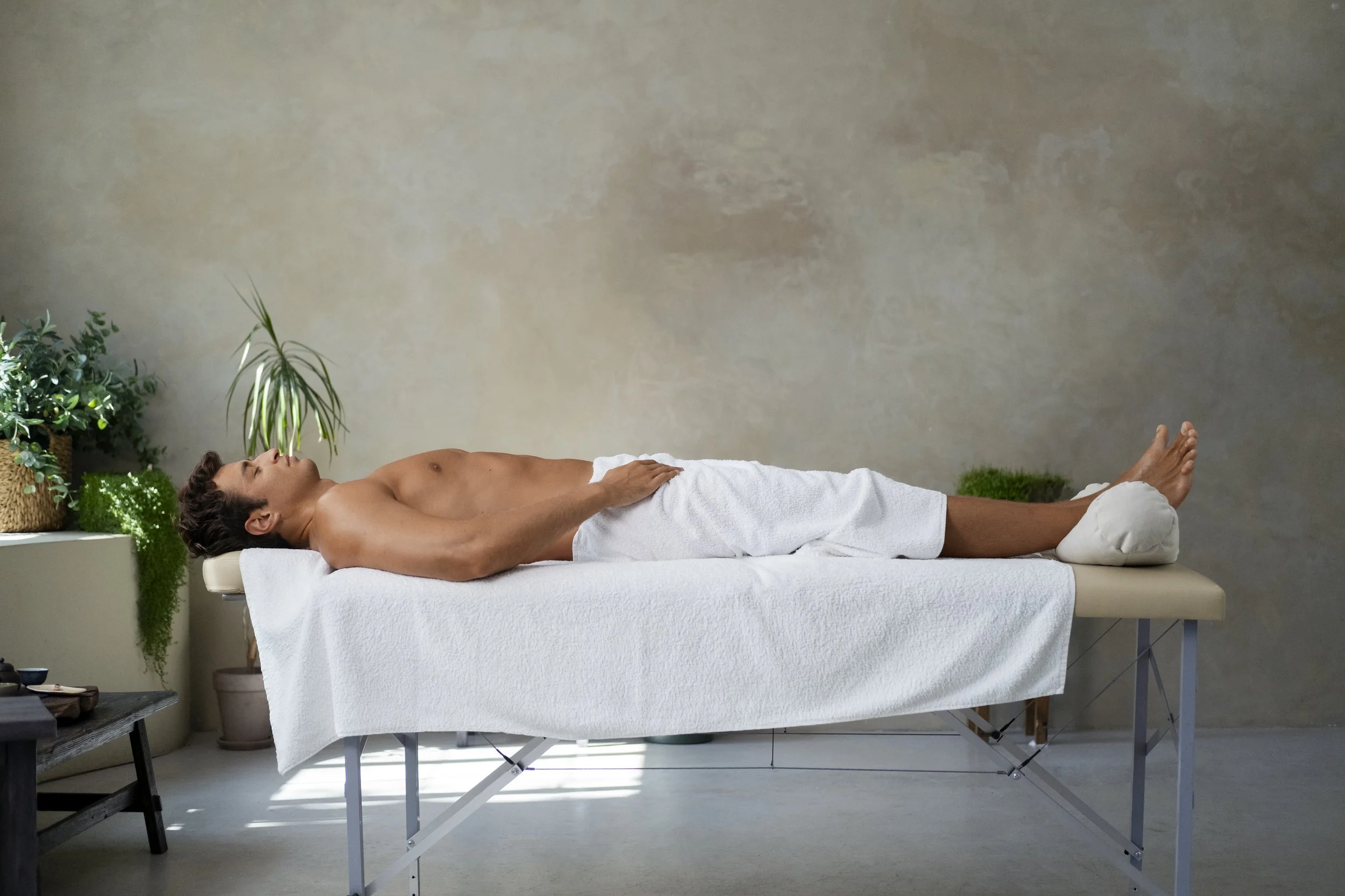 Client relaxing on massage table, ready for legs waxing with soft wax