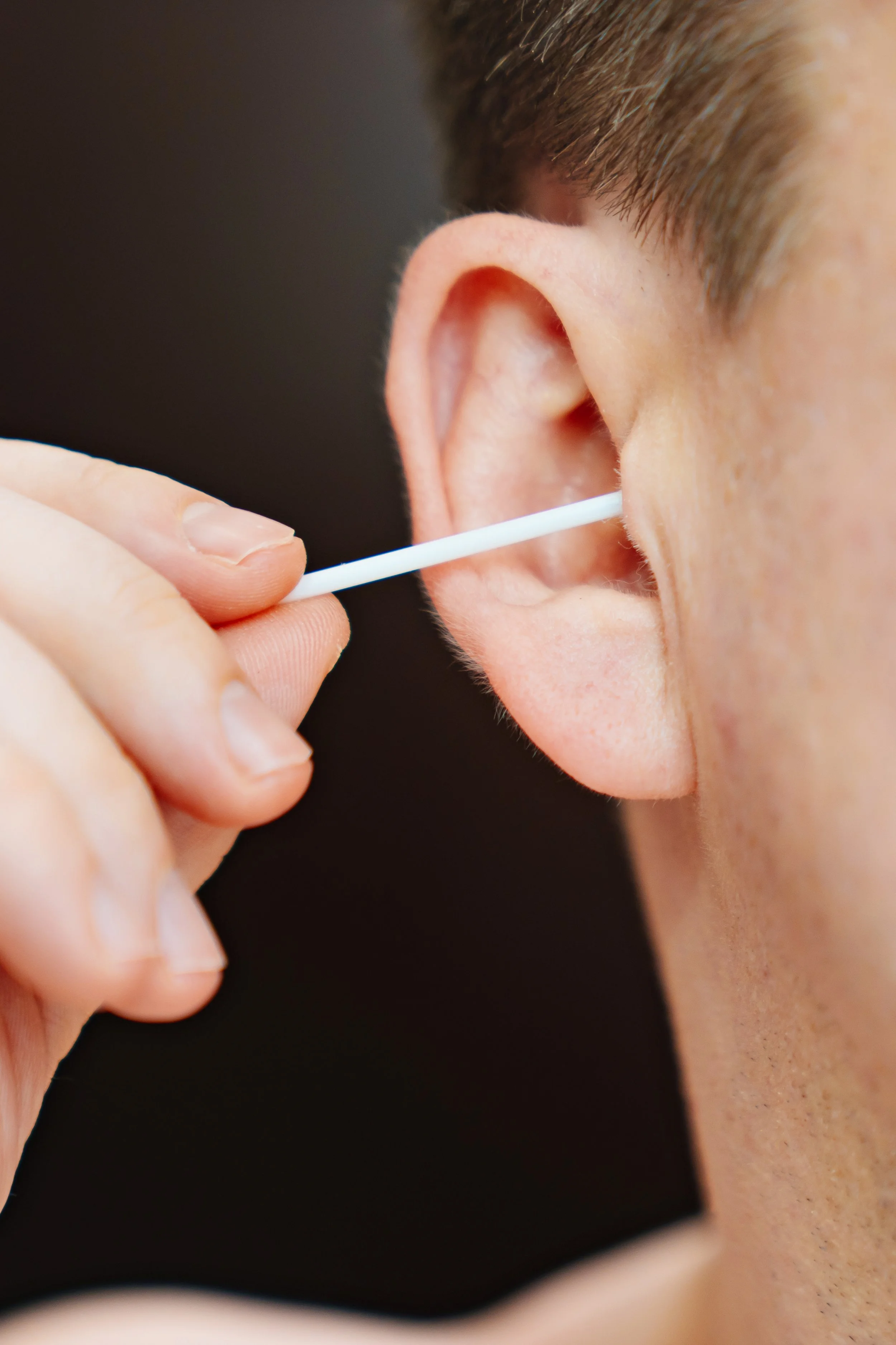 Close-up of ear hair removal using a tool, part of nose and ears waxing service with hard wax