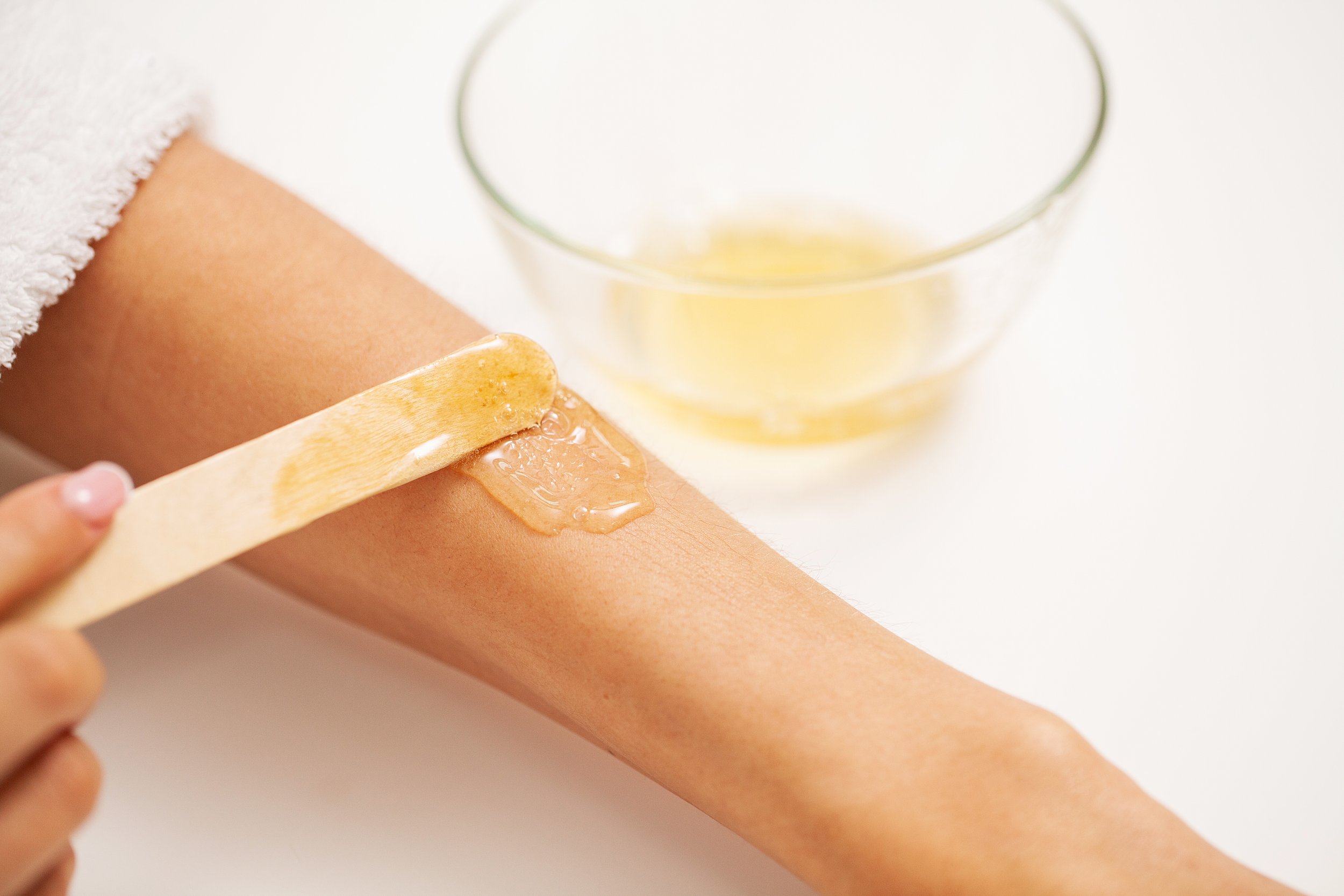 Wooden stick used to spread soft wax on client’s arm
