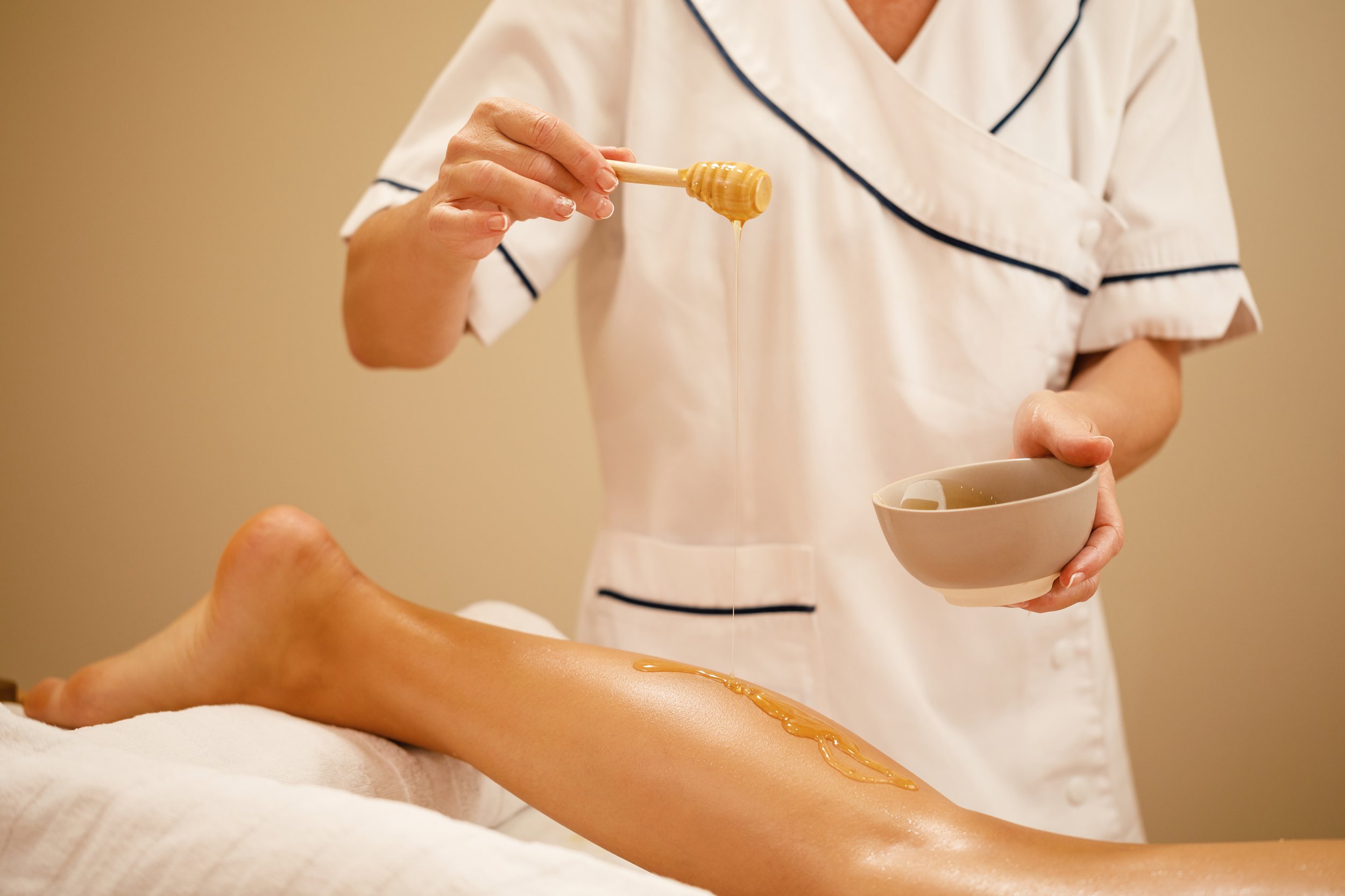 Leg waxing procedure: warm wax applied with wooden applicator, hygienic setup