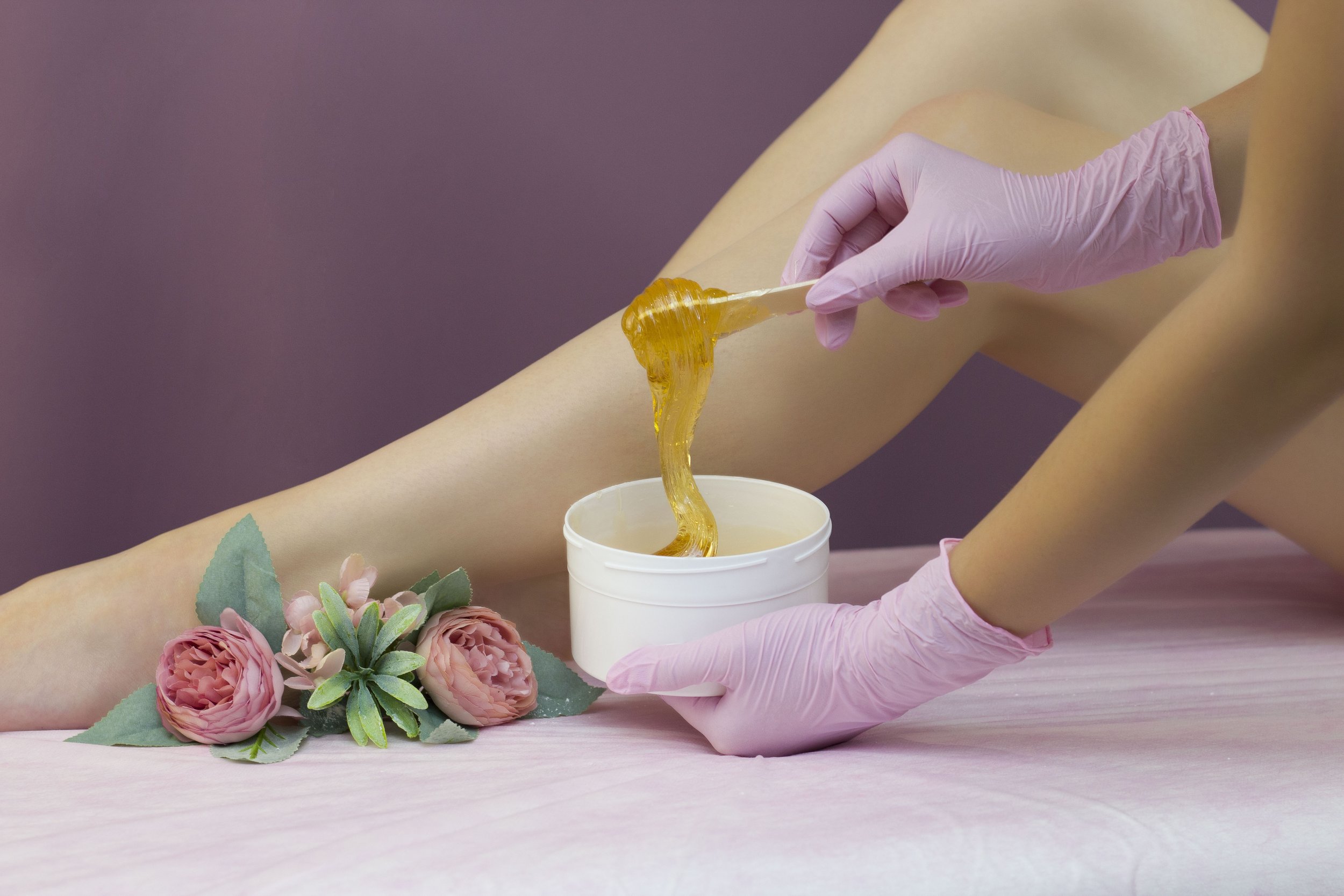 Full leg waxing service with disposable pink gloves and warm wax