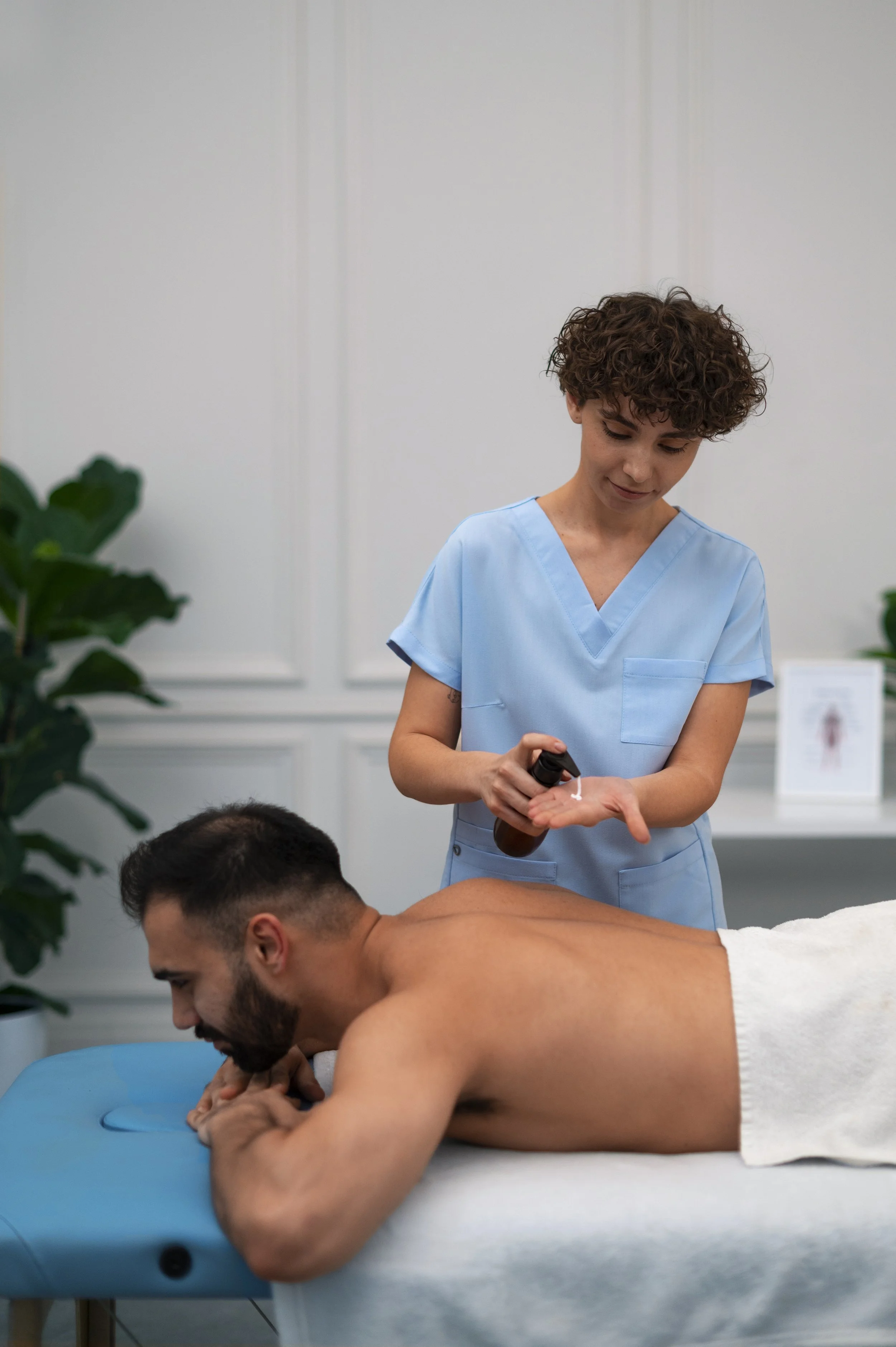 Therapist preparing massage oil for a male client.