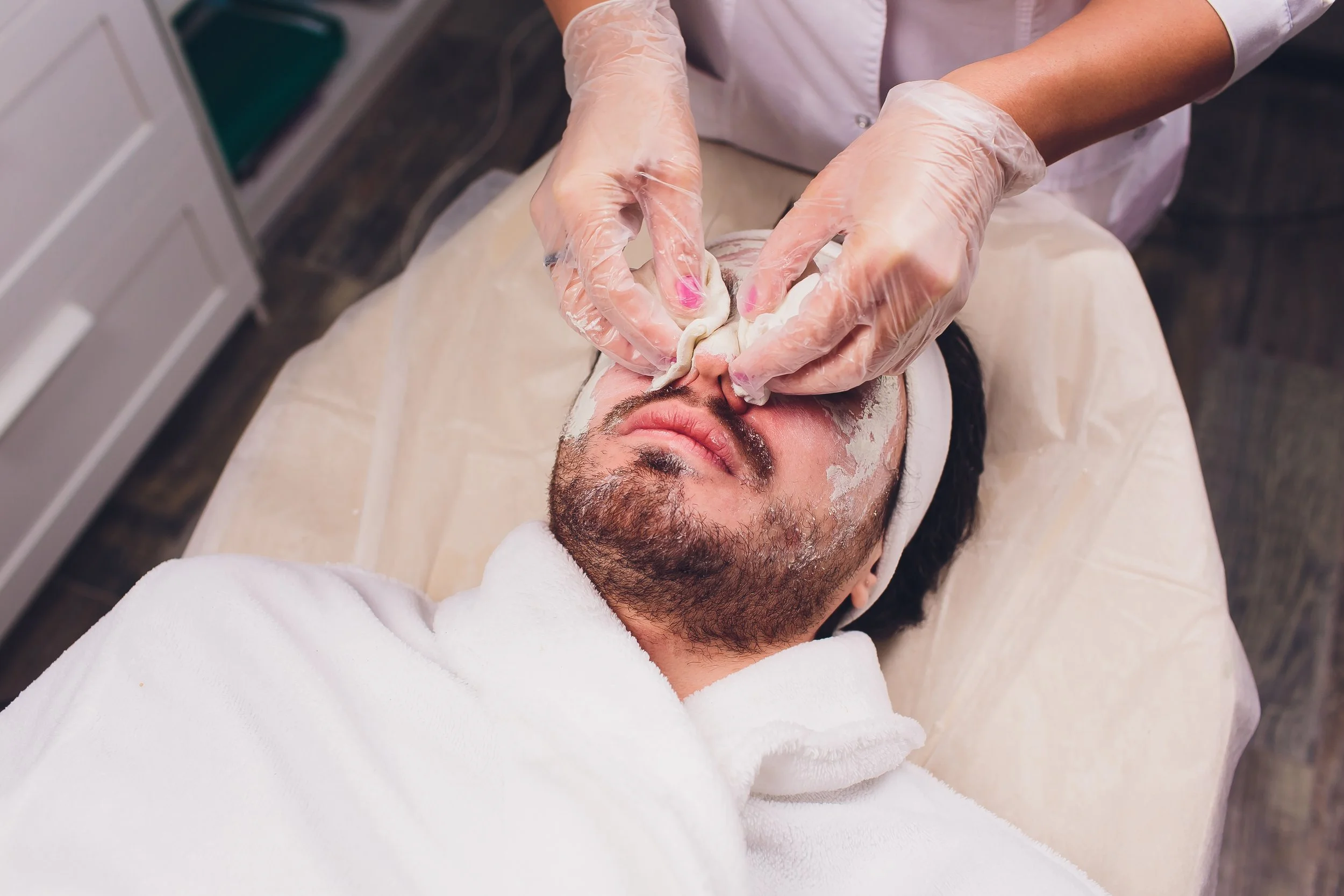 Client receiving nose and ears waxing treatment with hard wax, close-up view.