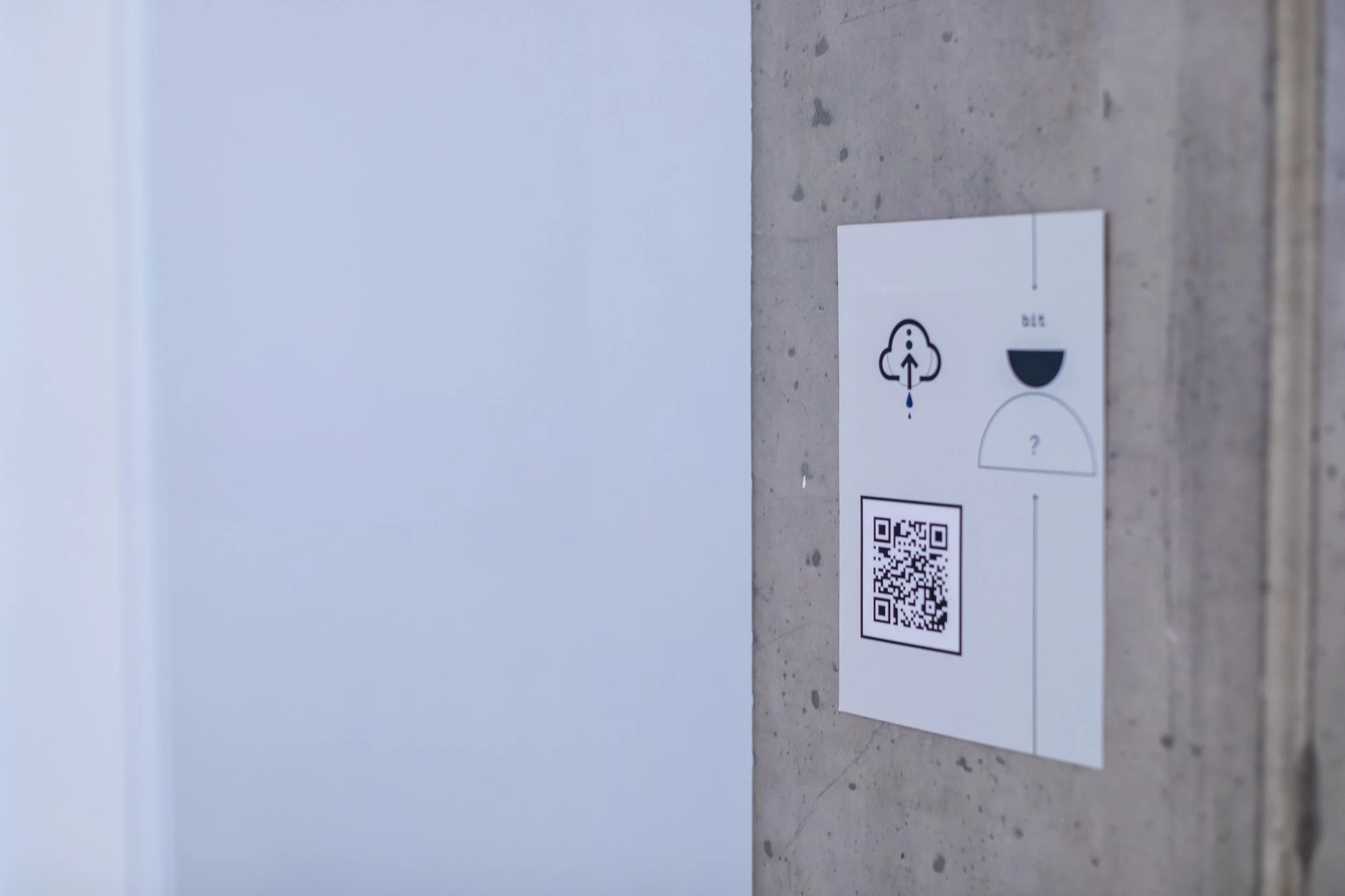A QR code stuck on a wall. There is a cloud image just above and text that reads: 'bit: ?'.