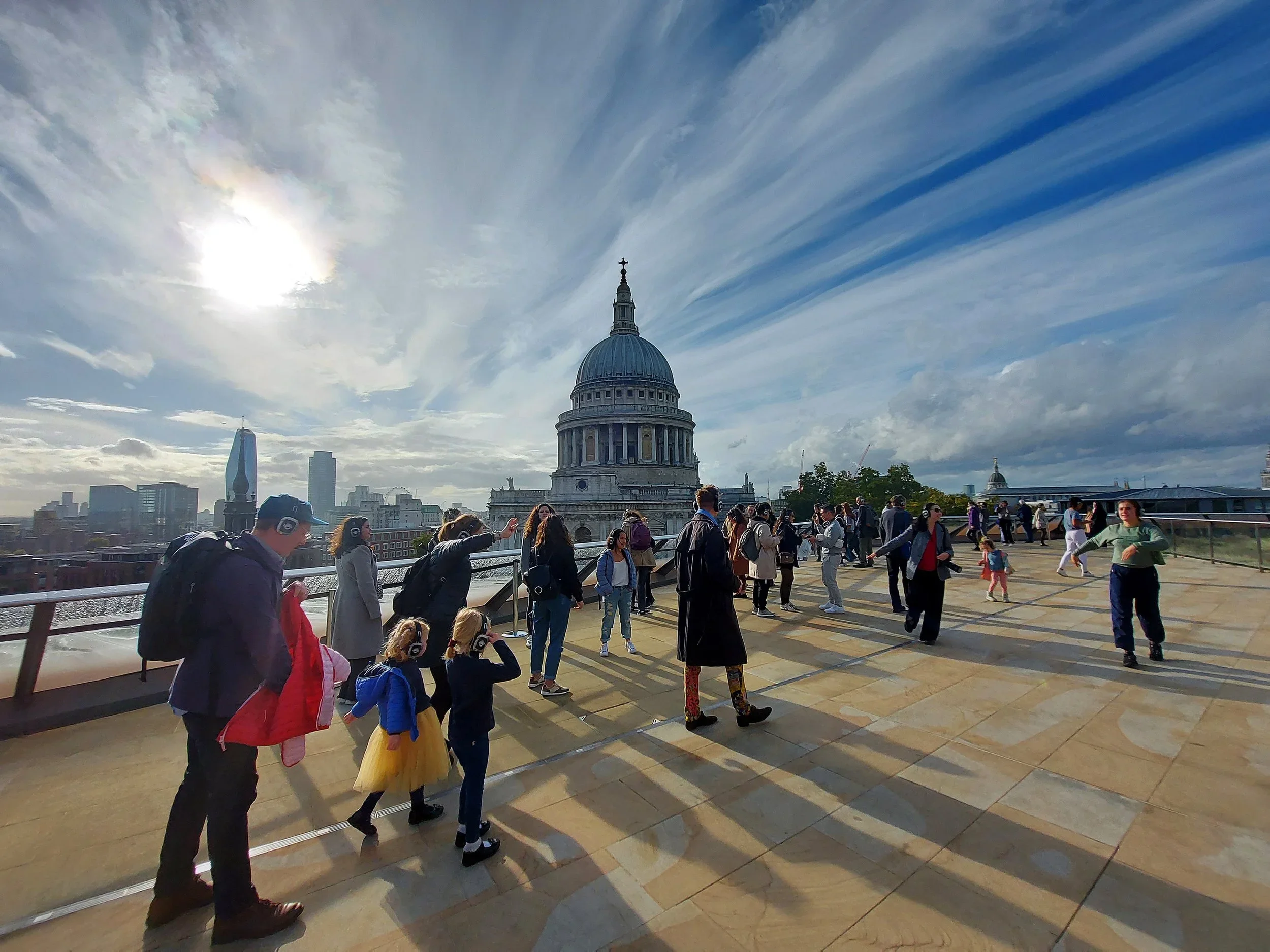 A group of audience member in headphones walk in front of St Paul's Cathedral