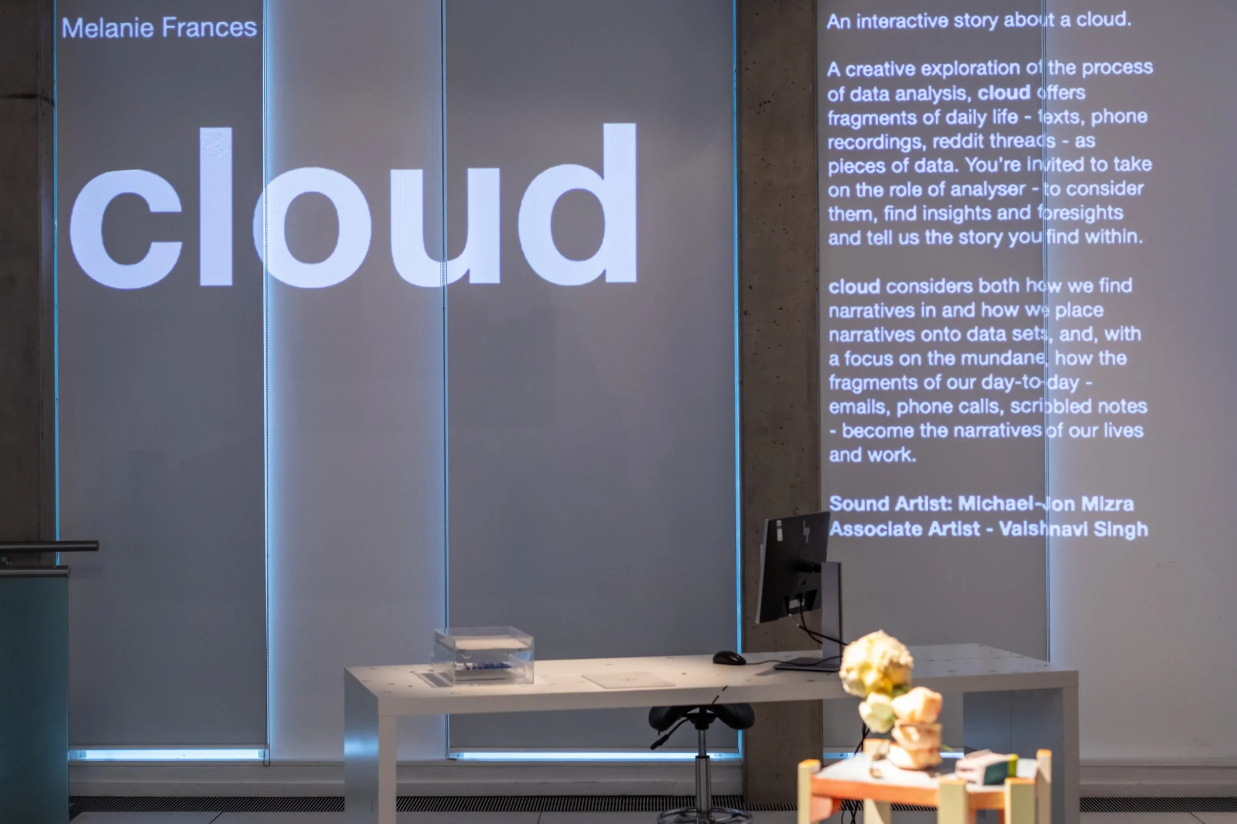 The word 'cloud' in white projected on on the wall. Paragraphs of text on the right describe the project.