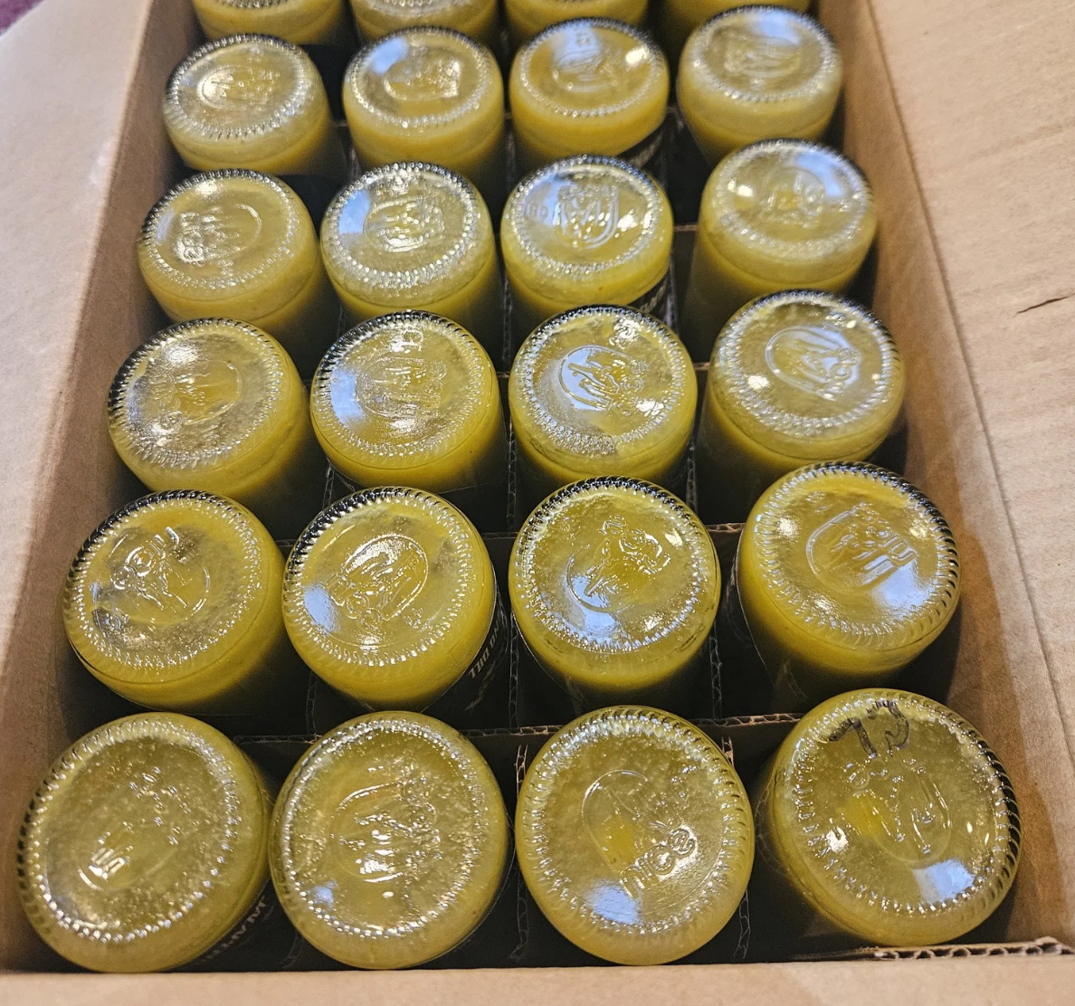 Box of 20 small yellow bottles with sealed tops, arranged in four rows of five, inside a cardboard shipping box.