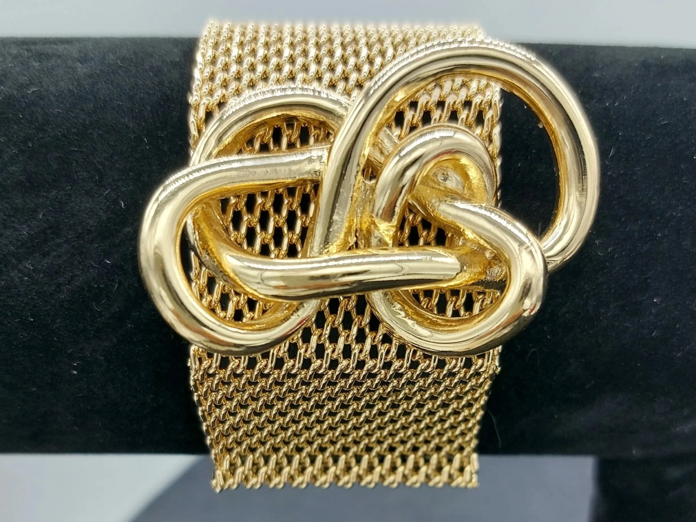 Gold chain-link bracelet with a large decorative gold and silver knot centerpiece.