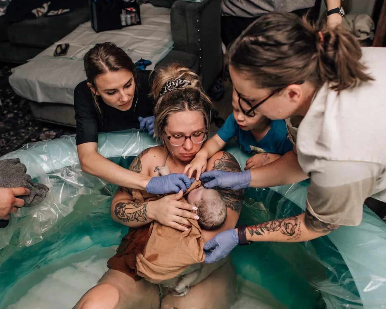 A woman giving birth in a pool with medical professionals assisting, in a home or clinic setting.