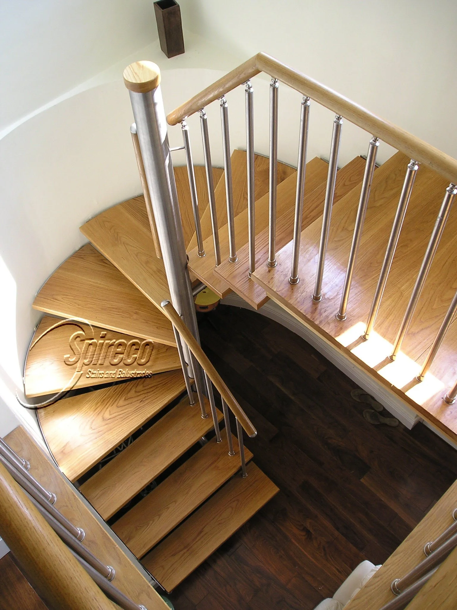 ‘Turner’ Stairs. Bespoke Stairs with 2″ American White Oak treads, connected to wall and Stainless Steel central column, with Circular Oak handrail & tubular Stainless Steel Spindles.